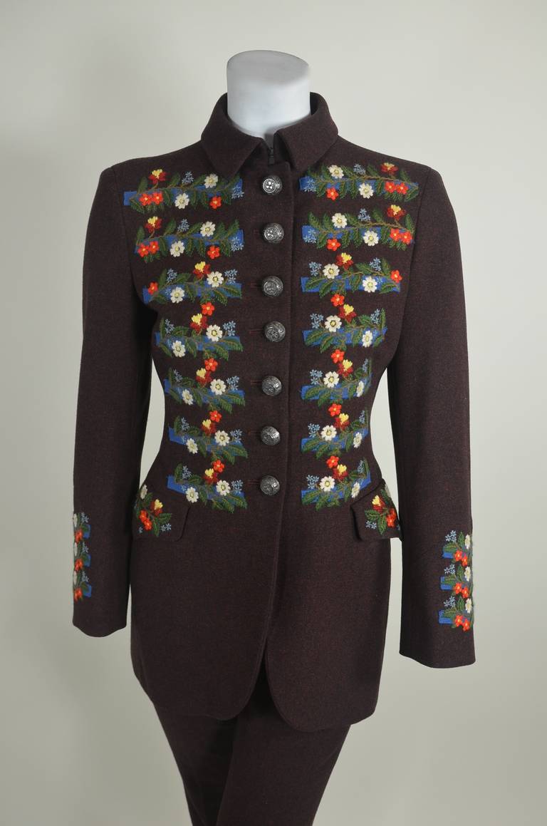 A beautifully tailored brown tweed suit from Moschino Couture. The luxe jacket is accented with floral embroidery in a Tyrolean motif. Stylized stamped floral buttons. Fully lined.

Jacket
Bust: 34 inches
Waist: 28 inches
Hip: 36