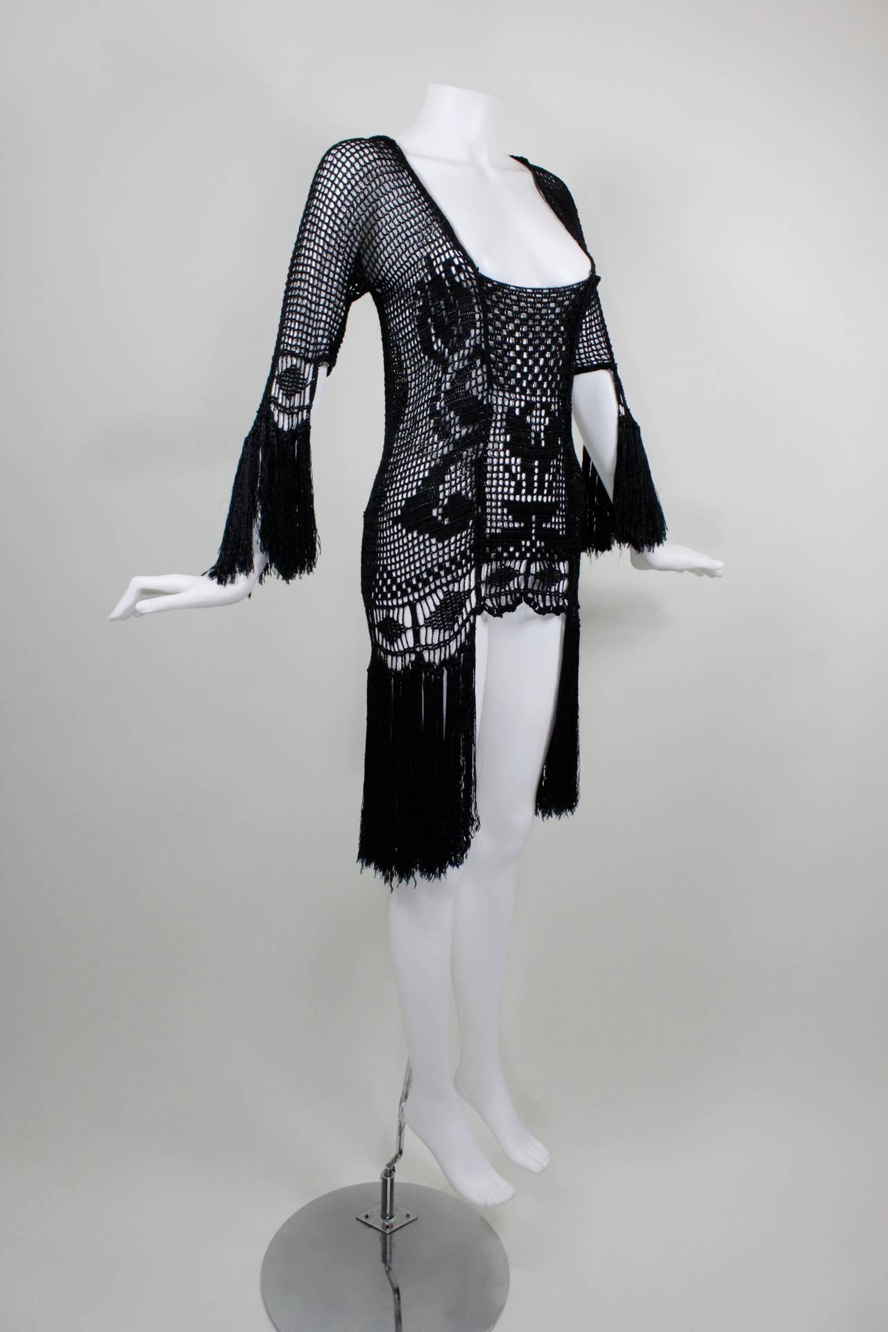 This is a jaw-dropping example of the gorgeous works of art that came out of the 1920s! Done in jet black, this crochet jacket features a geometric motif, and is trimmed in fabulous, scallop hem fringe on the hem, sleeves, and across the back