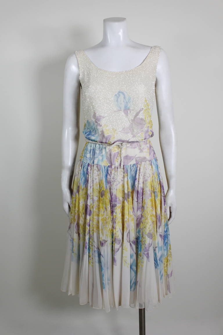 A flirty, fun, and chic party dress from the early 1960s. Evoking the delicate and painterly florals of 1930s chiffon gowns, this dress features a blue, purple, and yellow floral chiffon. A beaded bodice adds subtle sparkle and texture to the dress.
