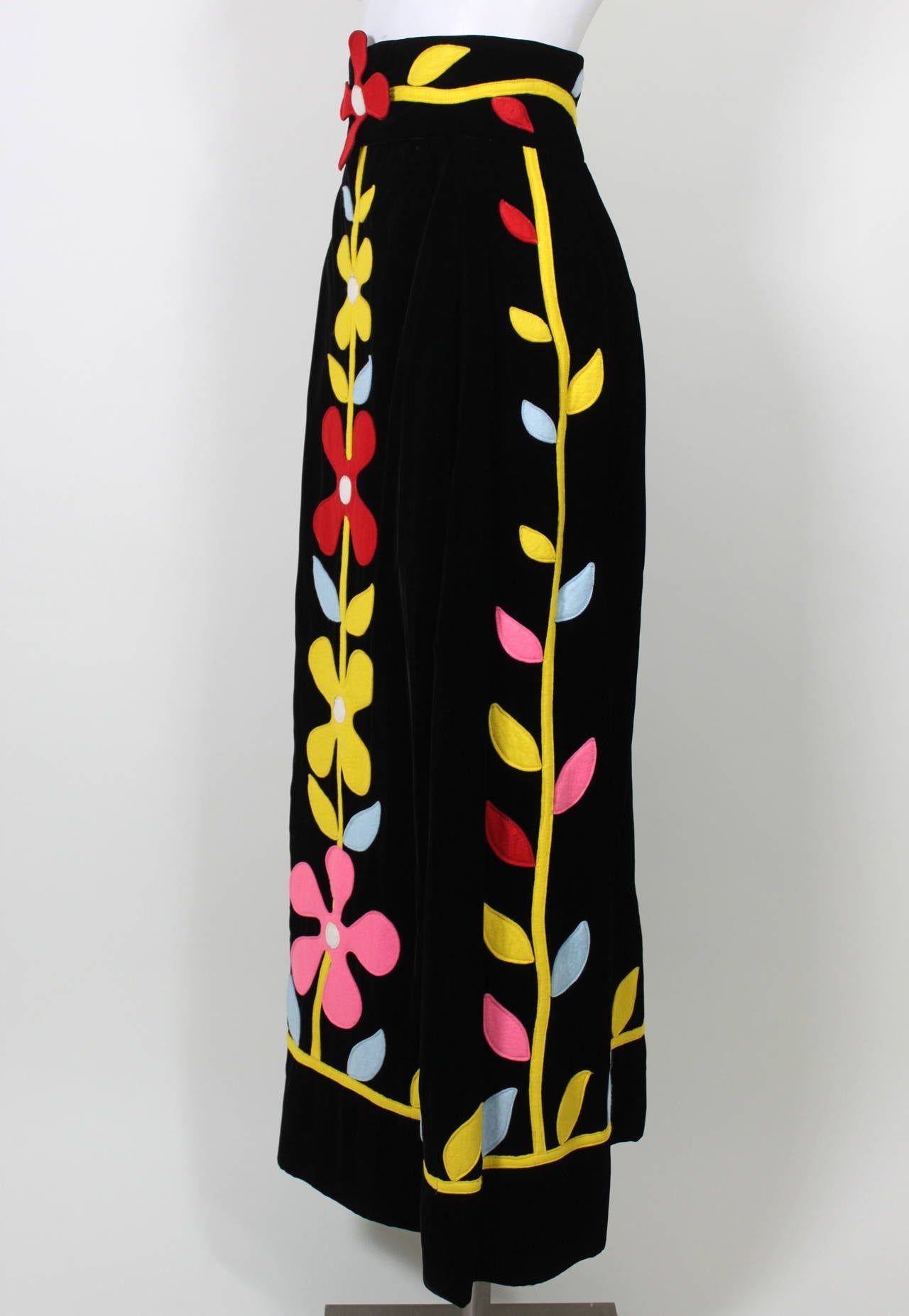 A fabulous mod skirt from Malcolm Starr done in a luscious black velvet and covered in mod felt floral appliqués throughout. It's bold, whimsical, and perfect for fall!

Measurements--
Waist: 26 inches
Hip: 34 inches
Length, Waist to Hem: 42