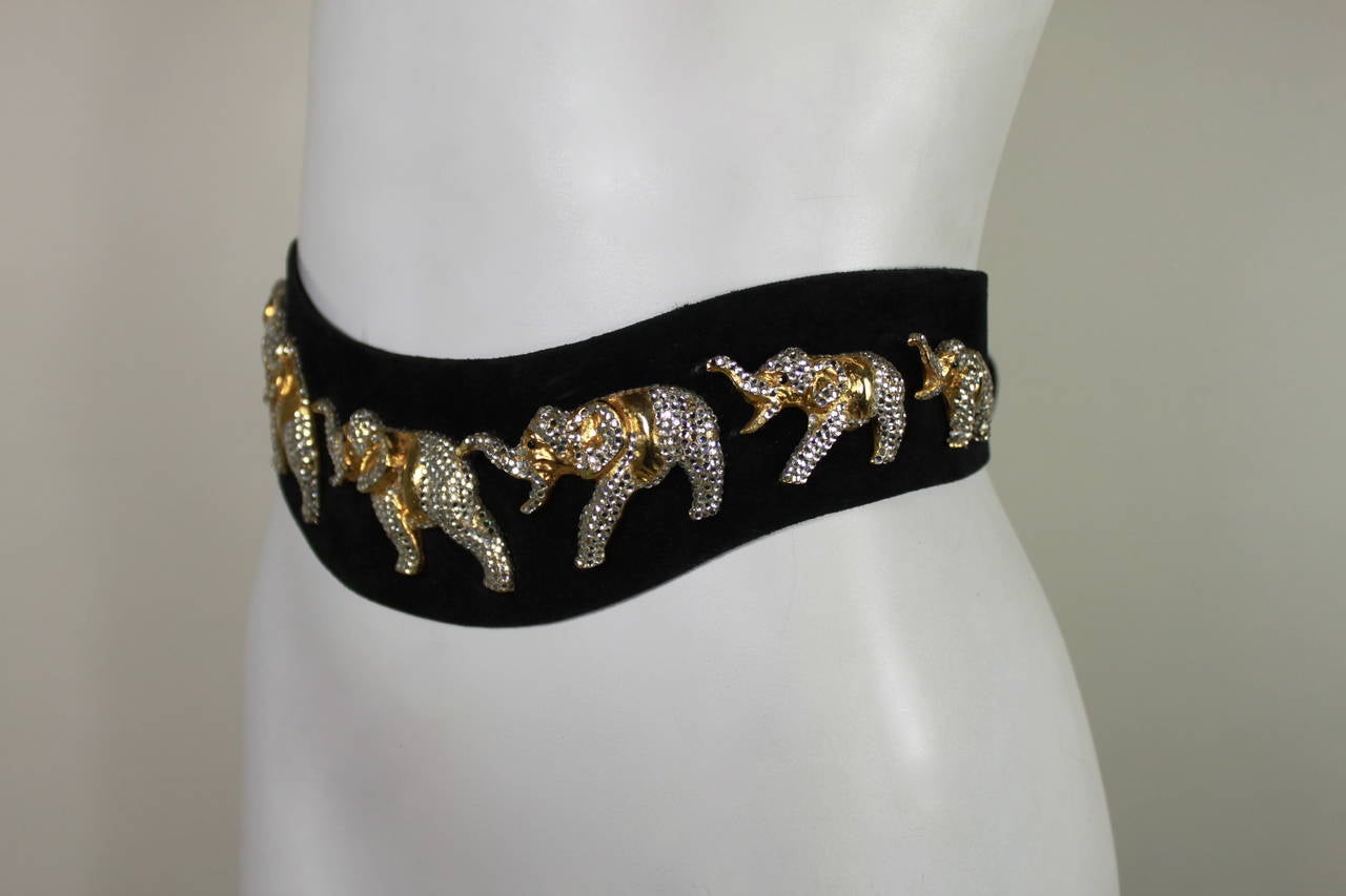 A fabulous statement belt from the 1980s, handmade in Austria. The black suede asymmetrical belt features seven rhinestoned elephants marching along the front. Belt has closure in back.