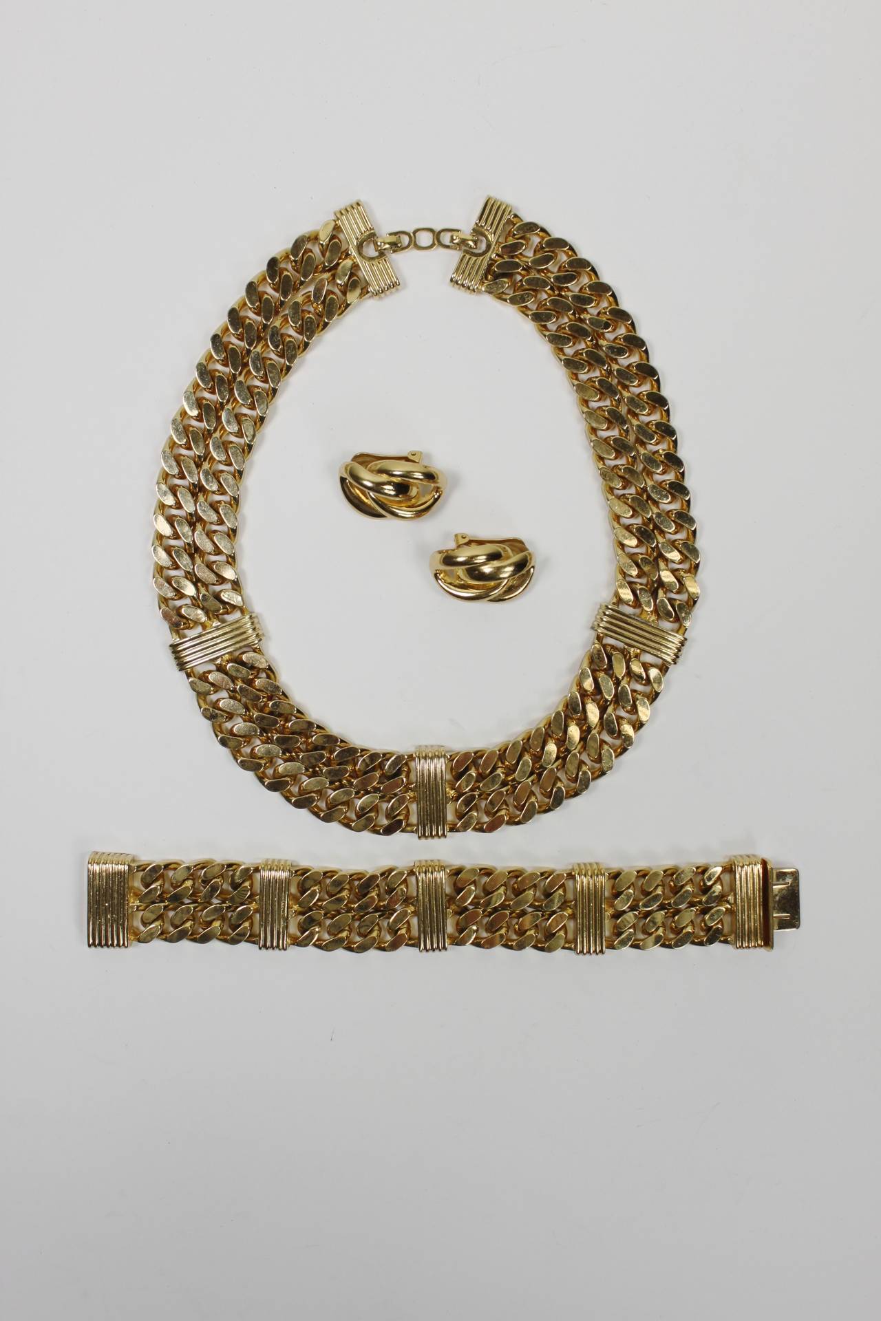 A stunning costume jewelry set from Christian Dior. A necklace, bracelet, and earrings are done in a fabulous, glimmering gold-tone chain link. The metal is substantial and feels wonderful on. The gold-tone is gorgeously polished and