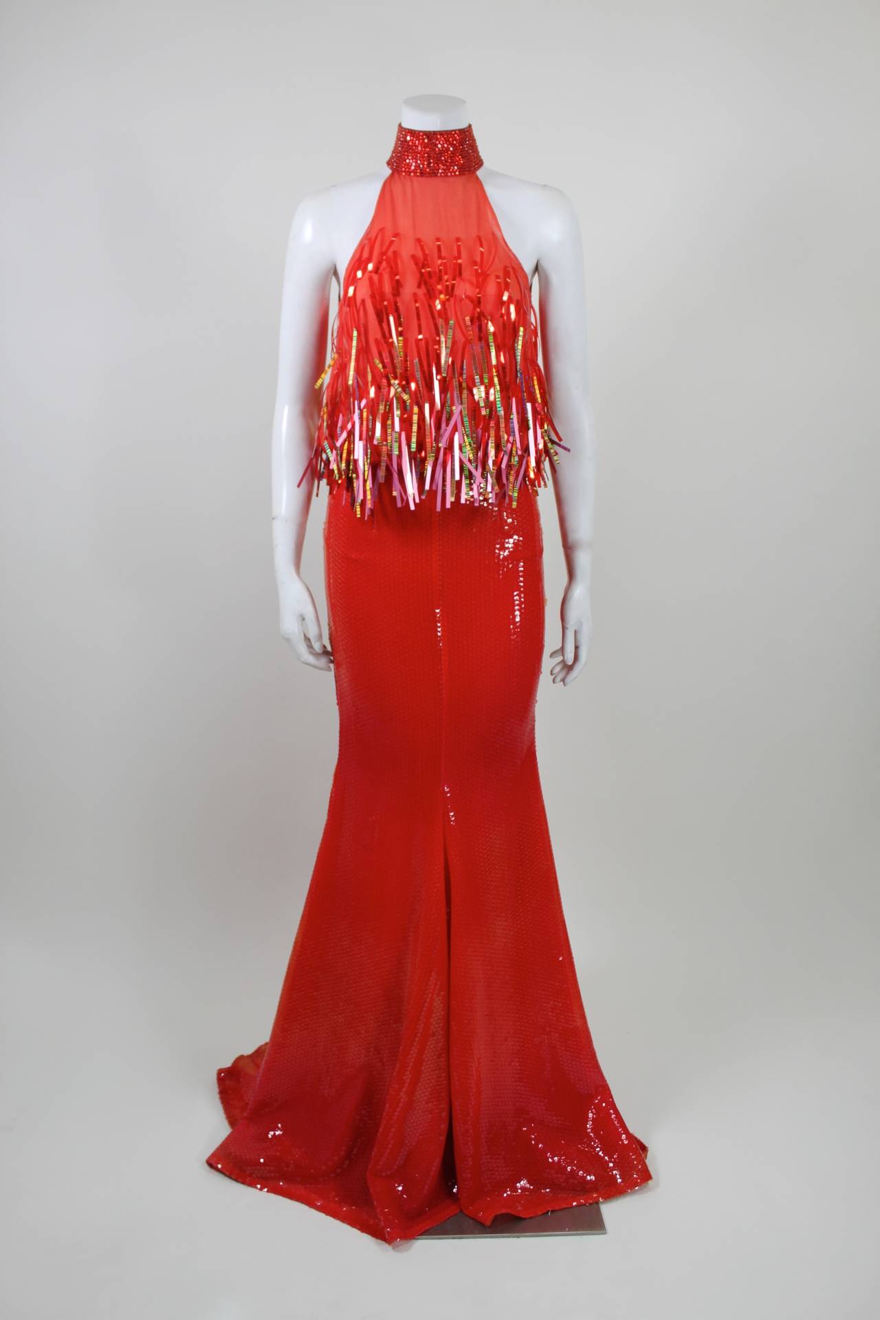 This 1990s evening gown is stunning on more than one level: it features gorgeous red and orange iridescent sequins throughout; the bodice is embellished with gorgeous, alternating color paillettes; and the silhouette is a halter with fitted mermaid