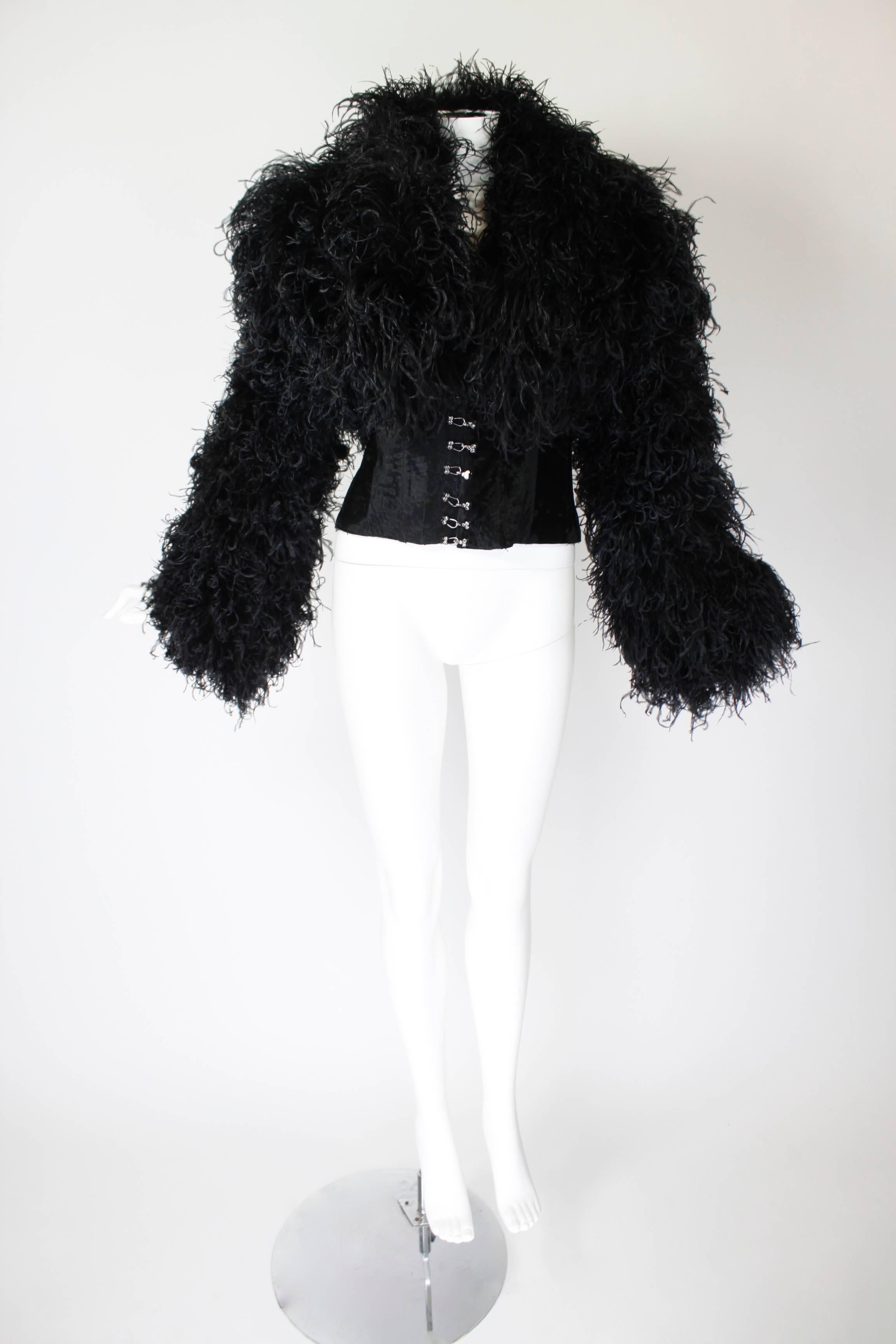 This wonderful evening jacket is done in luxe curled ostrich feather, creating unique, beautiful texture. The ultra fitted waist is done in karakul fur and features hook-and-eye closures with rhinestone detail. Partially lined in