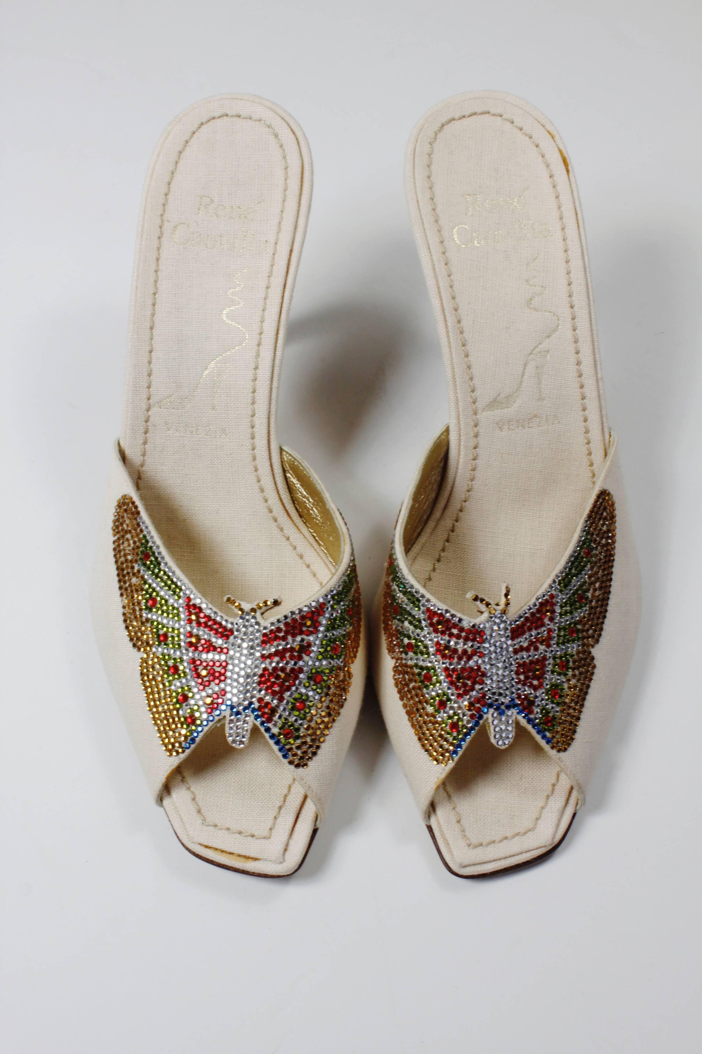 These fabulous cream mules from René Caovilla feature beautiful butterflies spreading their rhinestone wings across the shoe. 

Marked a size 38.