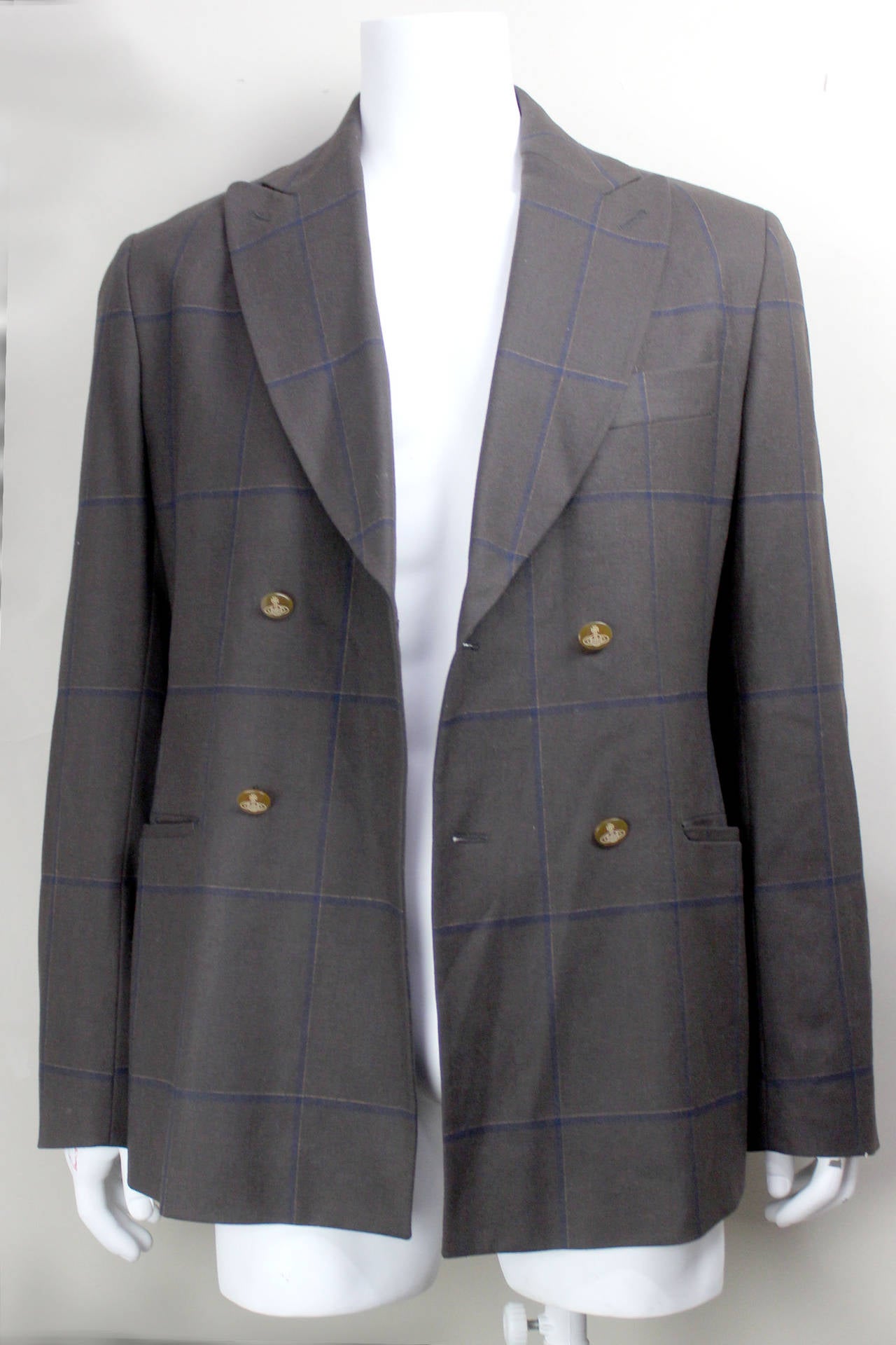This handsome double breasted jacket features one of Westwood's iconic tartan patterns. Since her Anglomania collection (AW 93/94) tartan prints have been a staple in Westwood's collections. This classic jacket is done in a stone grey with navy and