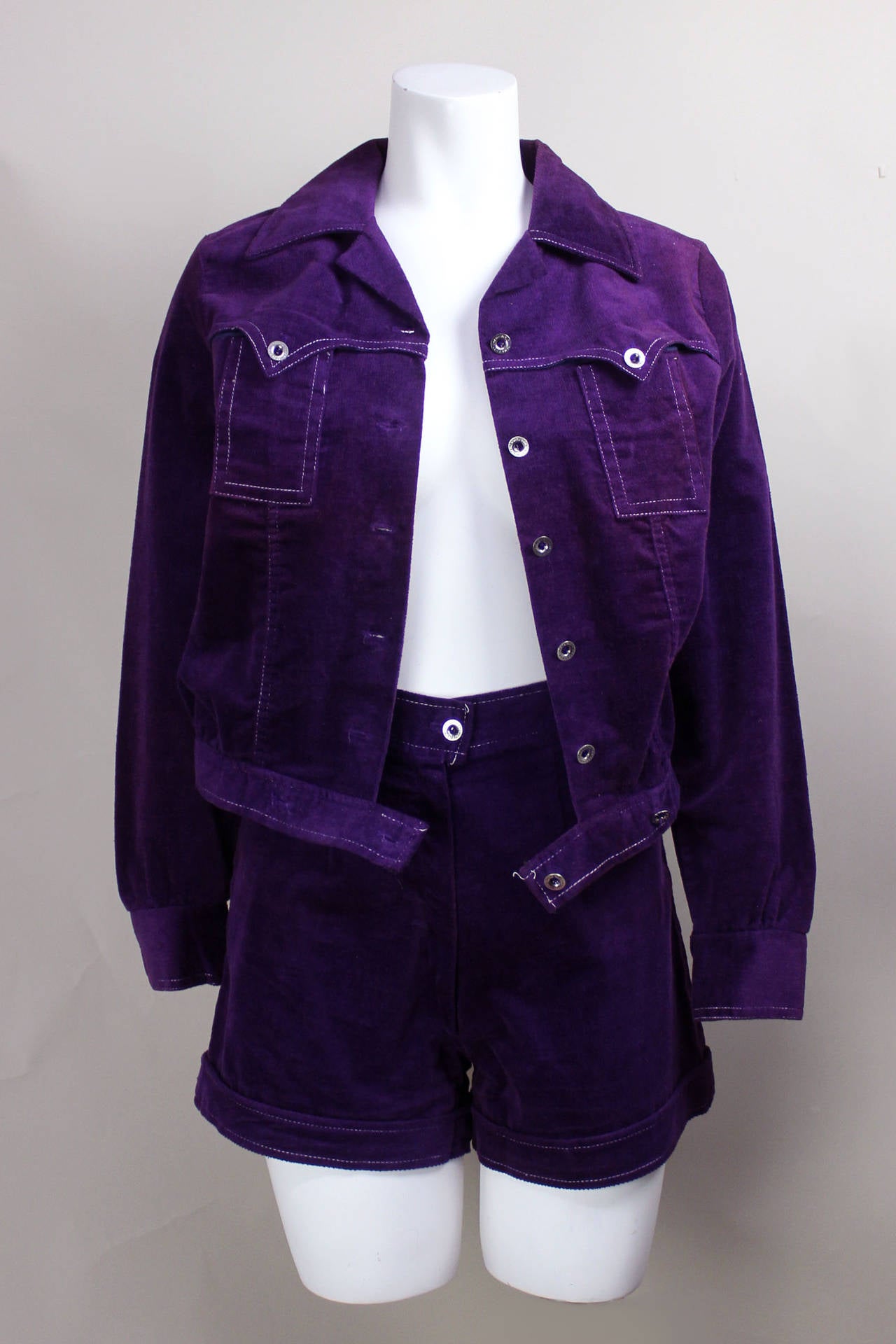 This hot pant and matching cropped jacket are cut from a soft and rich purple velveteen corduroy. The shorts are high waisted with a perfect little 1.5” cuff. The jacket is an incarnation of a classic denim jacket, with two breast pockets and
