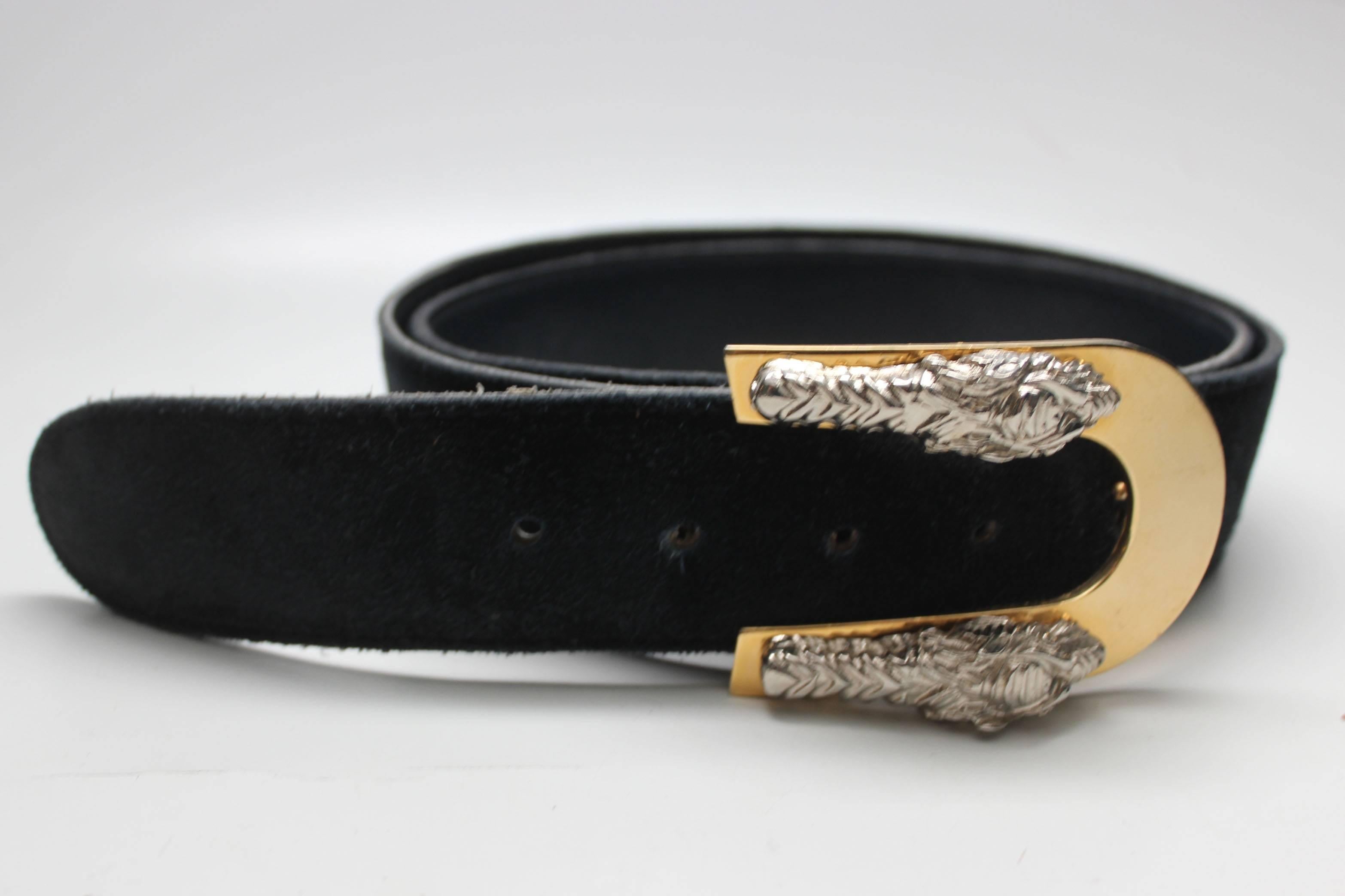 This vintage Jaeger belt makes a bold statement with its gold and silver dragon buckle. The two silver colored dragon faces sit on a gold buckle with a hook on the back. The navy belt is suede on the outside and leather inside, marked as size 34,