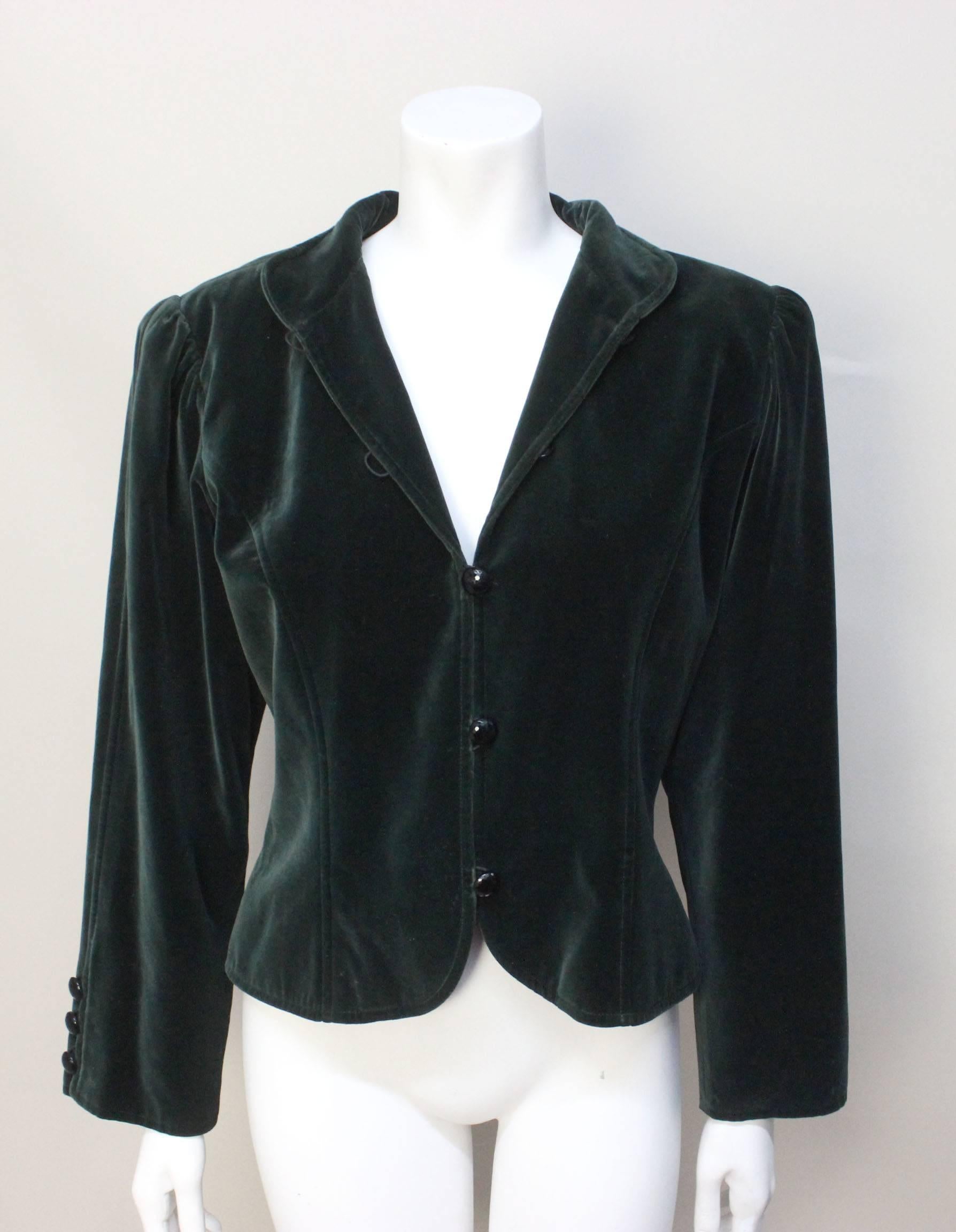 Yves Saint Laurent often referenced folkloric style in his Rive Gauche designs. This rich forest green velvet jacket has some such details with its puffed sleeves and Mandarin collar. The black cushin cut glass buttons add to the jacket's elegance. 