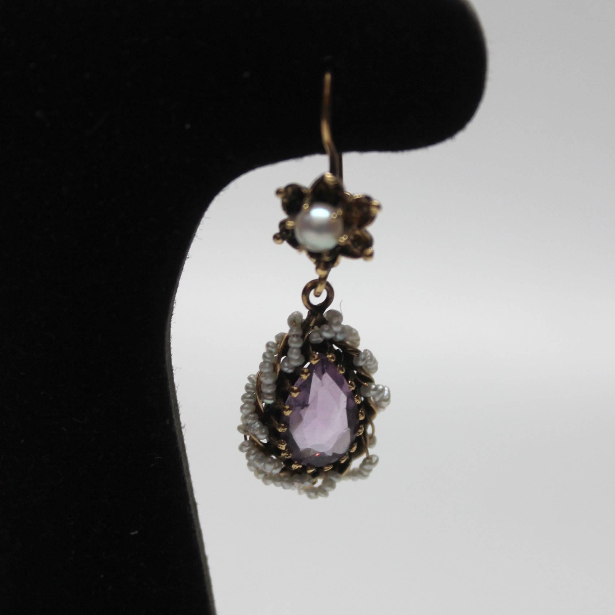 These Victorian era earrings are exquisite. A teardrop with an amethyst center is set in gold and encircled by delicate seed pearls. The post is star shaped and has a pearl at its center. The earrings are both marked with a 14k stamp. 