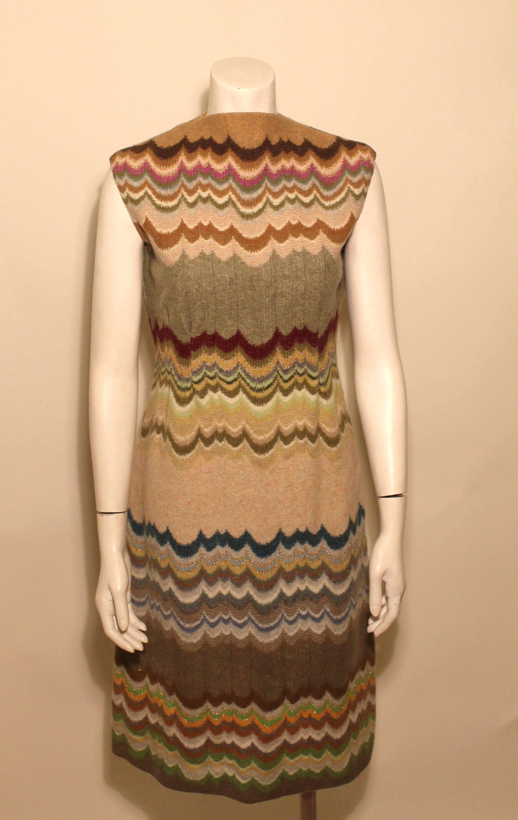 This Trigere dress is a colorful luxe wool in an unusual scallop design. The shades of neutral green and blues on the tan fabric have strips of gold lame through the design to add a subtle amount of shimmer. 