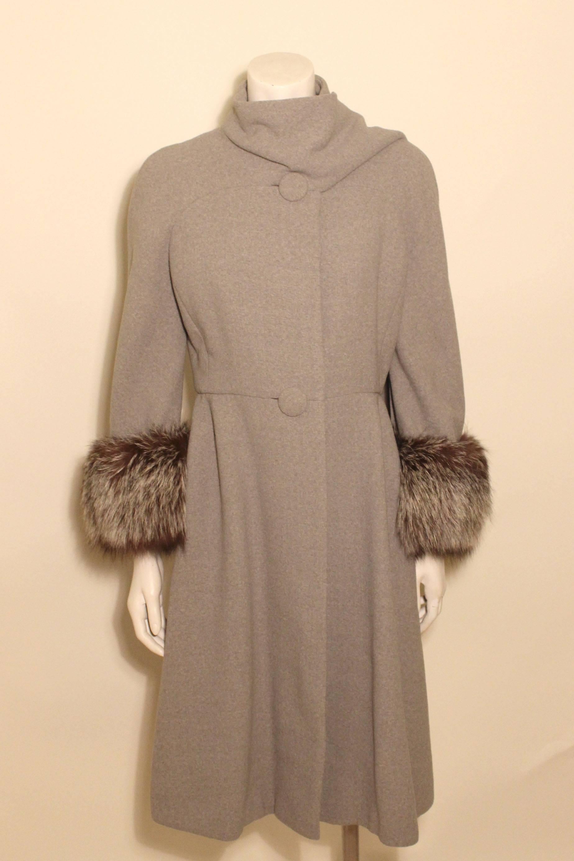 This coat has a chic and timeless design with a high draped neckline ending in a muffler. The shape is slightly A-Line with covered buttons.