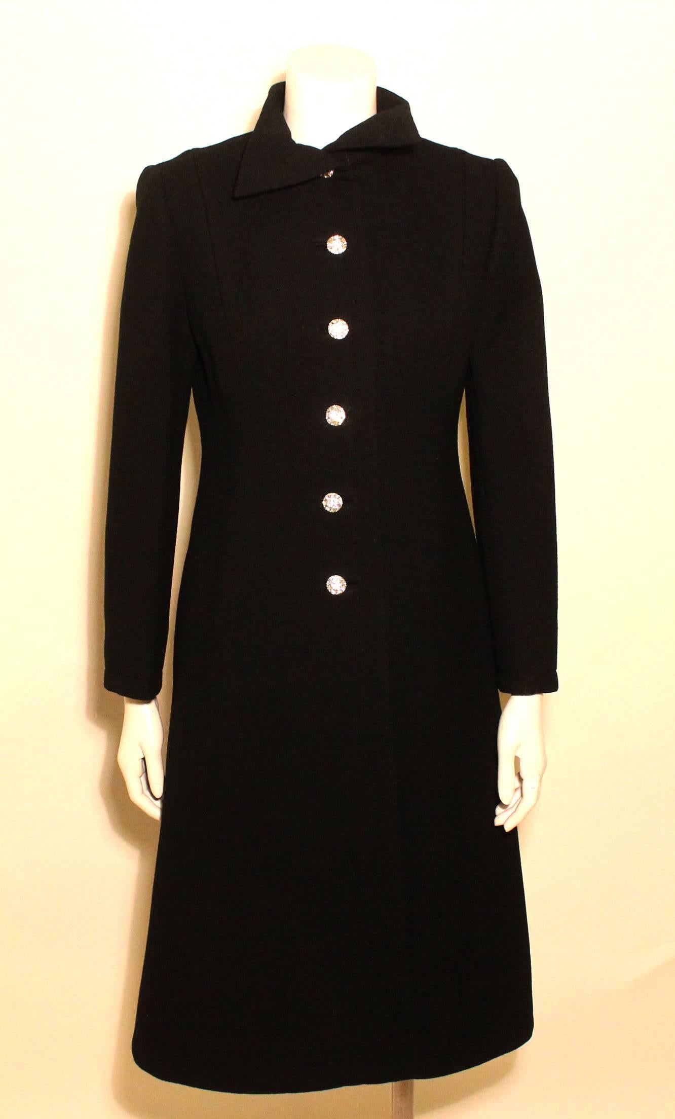 This is a stunning black wool evening coat with six rhinestone buttons down the front and back, with three on each sleeve. It is a classic a-line tapered shape. 