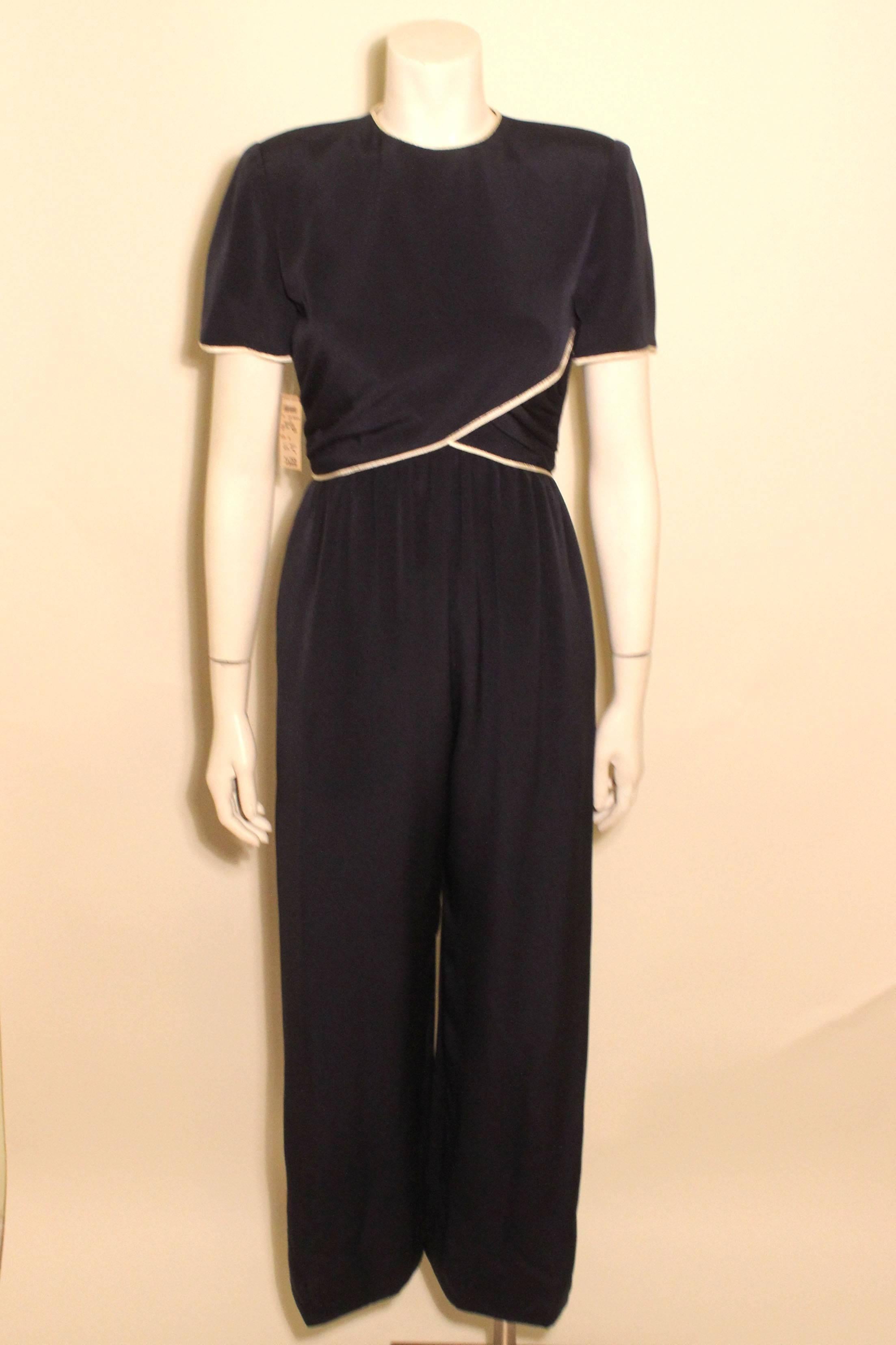 This Bill Blass jumpsuit is a chic navy silk with white piping detail. The top drapes nicely with side ruching. The fabric is slightly gathered at the waist, falling in graceful pleats to wide legs. The original Bergdorf Goodman tag is attached. 