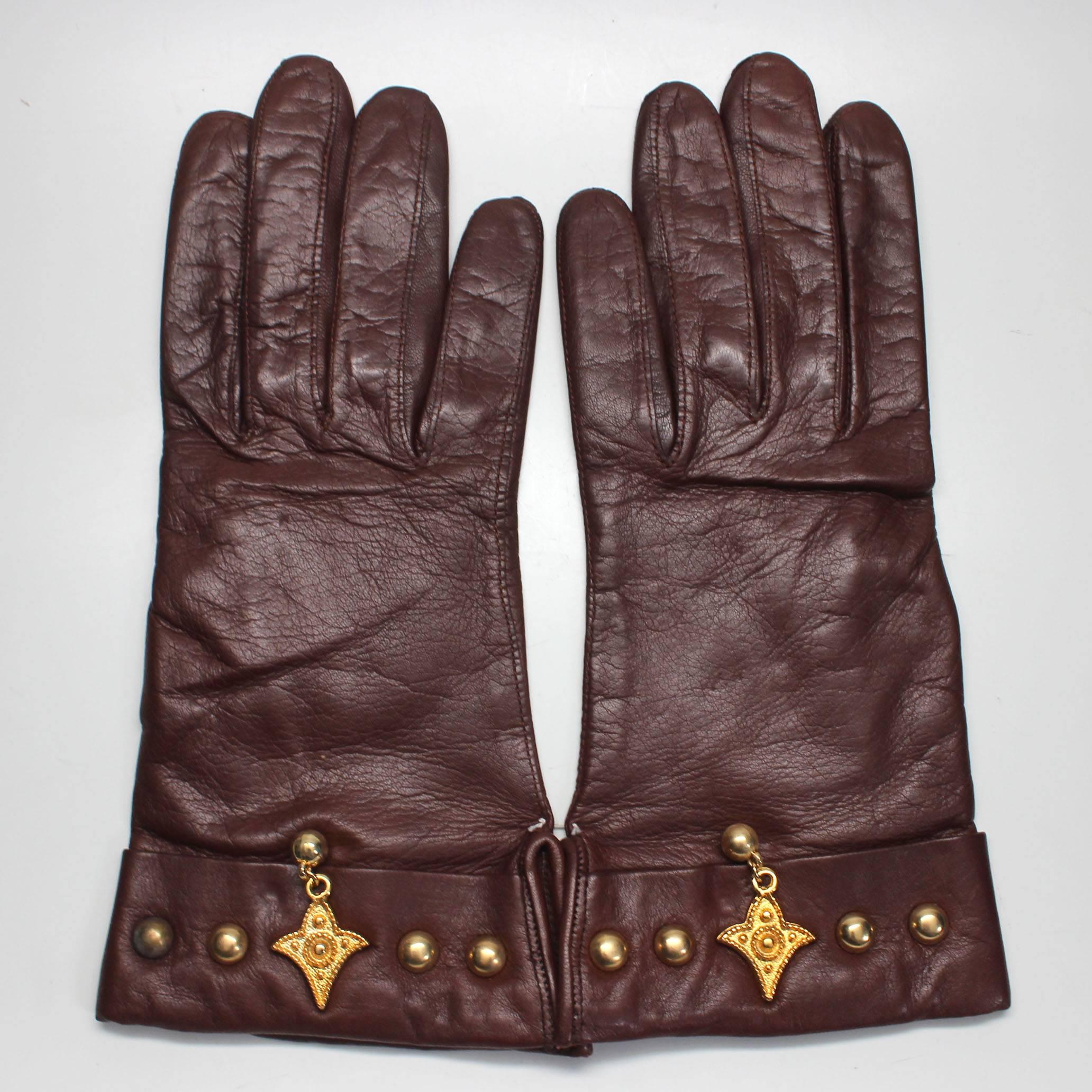 These soft leather gloves are the ideal Escada 80's accessory. This is a pair of never worn brown leather gloves with gold studs and charm at the wrist. The original Escada tag is attached, size 7.