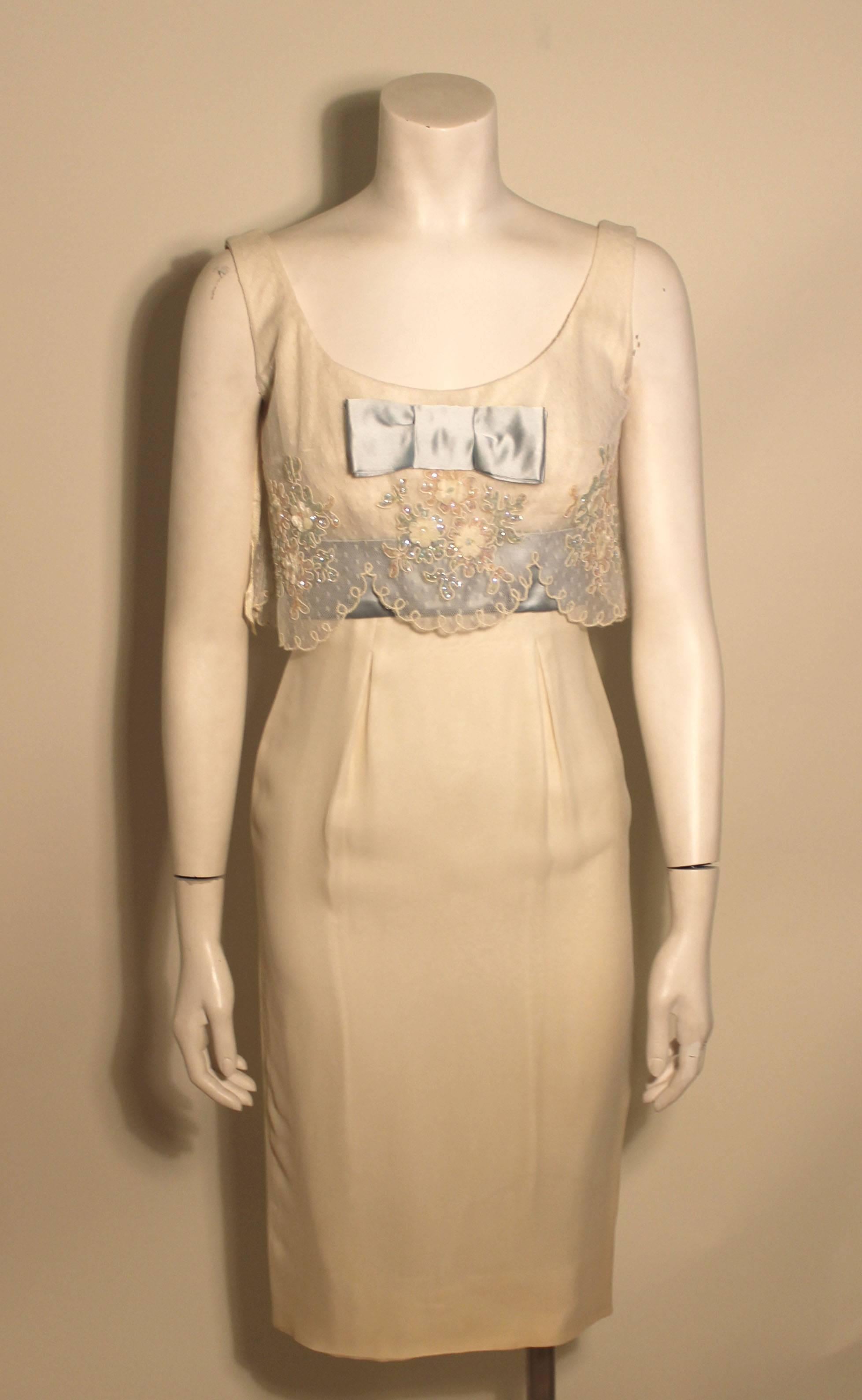 1960's style vintage creme silk crepe Oleg Cassini cocktail dress featuring a lace bodice embellished with sequined appliques and trimmed with pale blue satin ribbon.