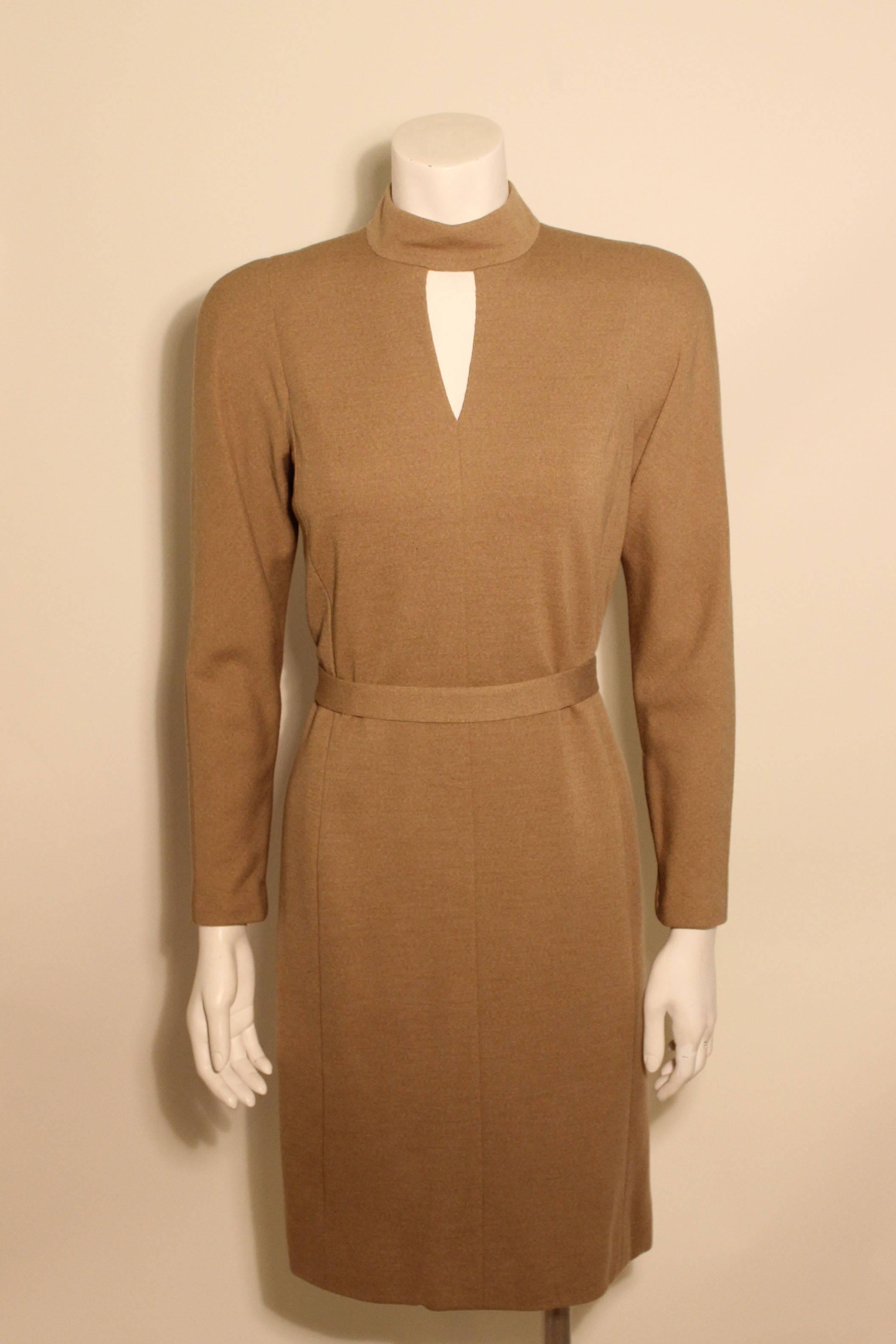 Vintage Pauline Trigere fine wool knit taupe sheath dress featuring a keyhole neckline and zippered sleeves. There is a detached belt that can be used to cinch the waist. The dress has a full silk lining. 