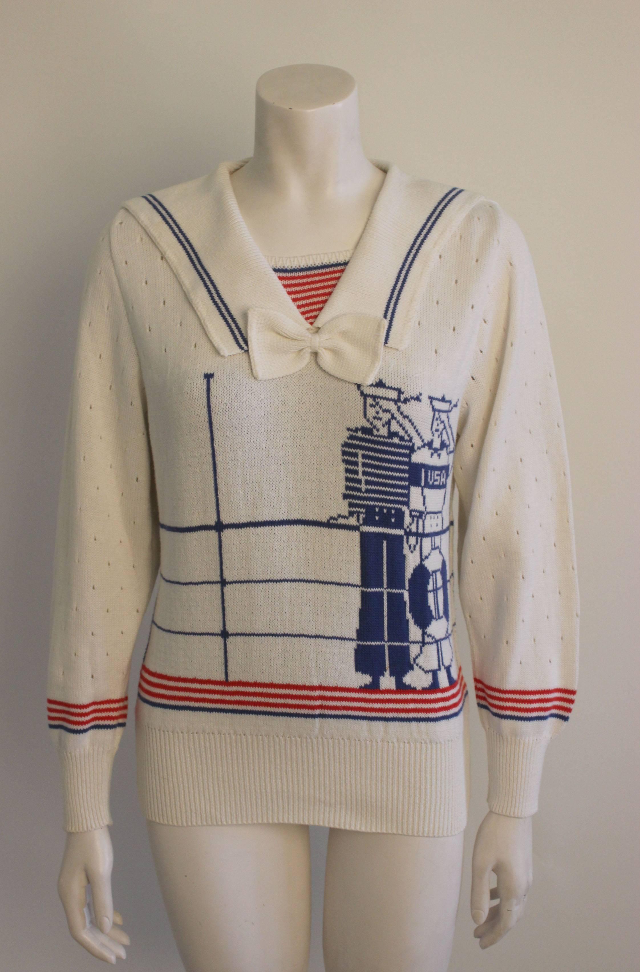 This cotton knit sweater by Ignacy Feuer has a wonderful graphic of two sailors standing shipboard. Other whimsical details add to the nautical theme: a knit tie under a sailor collar and a red & white stripe knit inset at the neckline. 