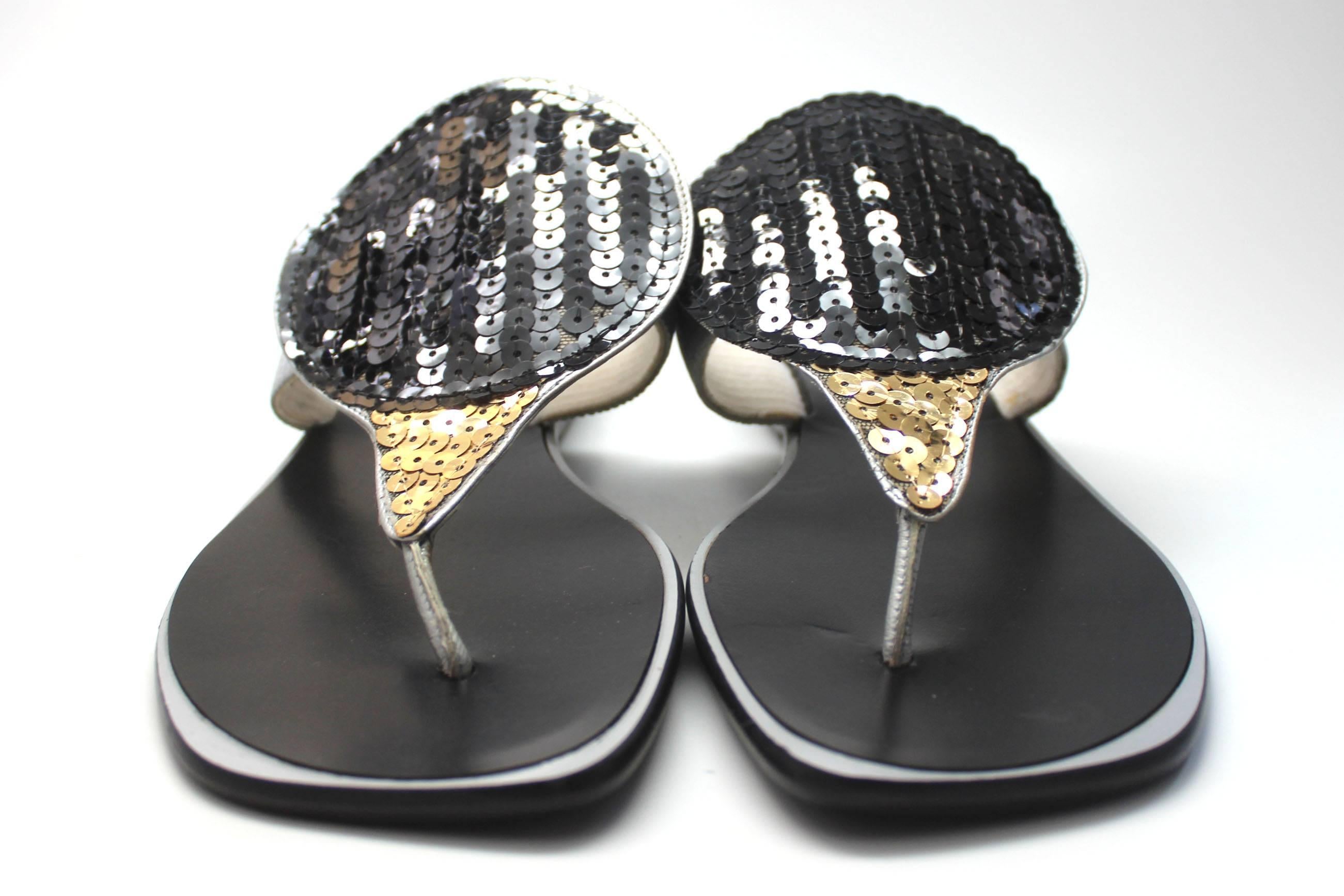 These futuristic style sandles have a large round disc covered in black sequins that extends into gold sequins towards the toes. They are in never worn condition and come with their original box. 