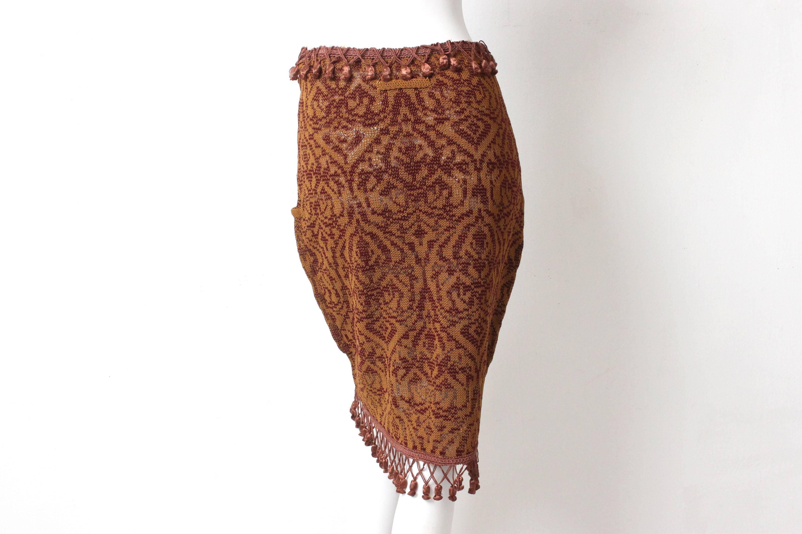 This skirt by Jean Paul Gaultier has a lush knit pattern and hugs the body perfectly with a fitted high waist. There are a row of tassels at the waist and at the hem. It is further adorned with two front pockets and a zippered front.