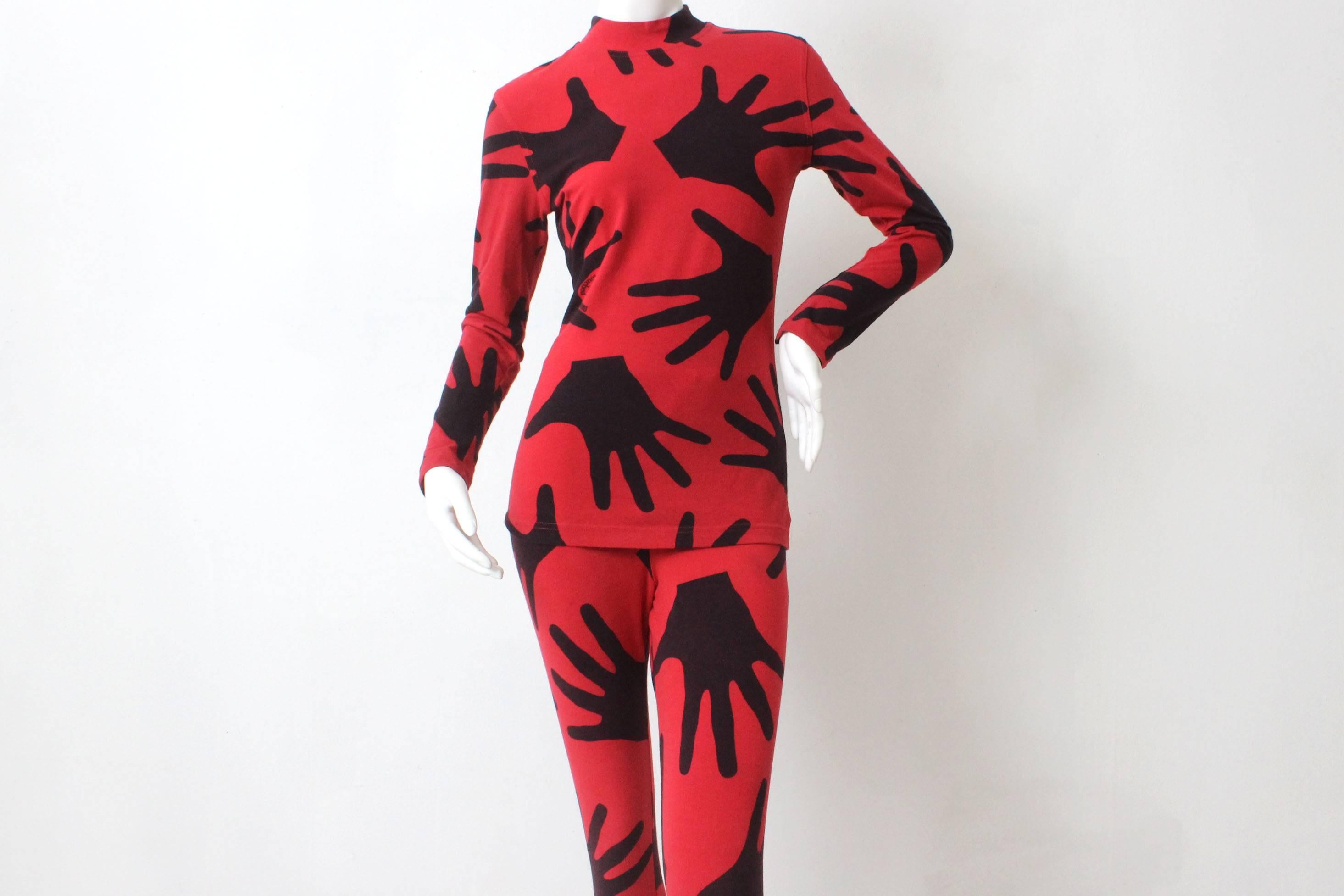 One of Franco Moschino's trademarks was his whimsical designs. This red and black two piece set is a perfect example of that. Around the fanciful pattern of hands is written "Touched By Moschino"  The label lists the size as a EU 46 but it