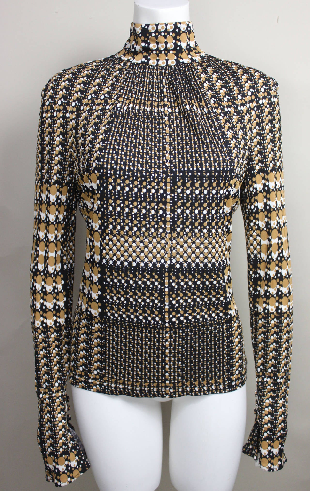 This slinky Versace blouse from the 1990's features a unique brown, black and white pattern. The op print when looked at from afar, create an illusion of an intricate  plaid. The blouse features a high neck with a four button closure and small