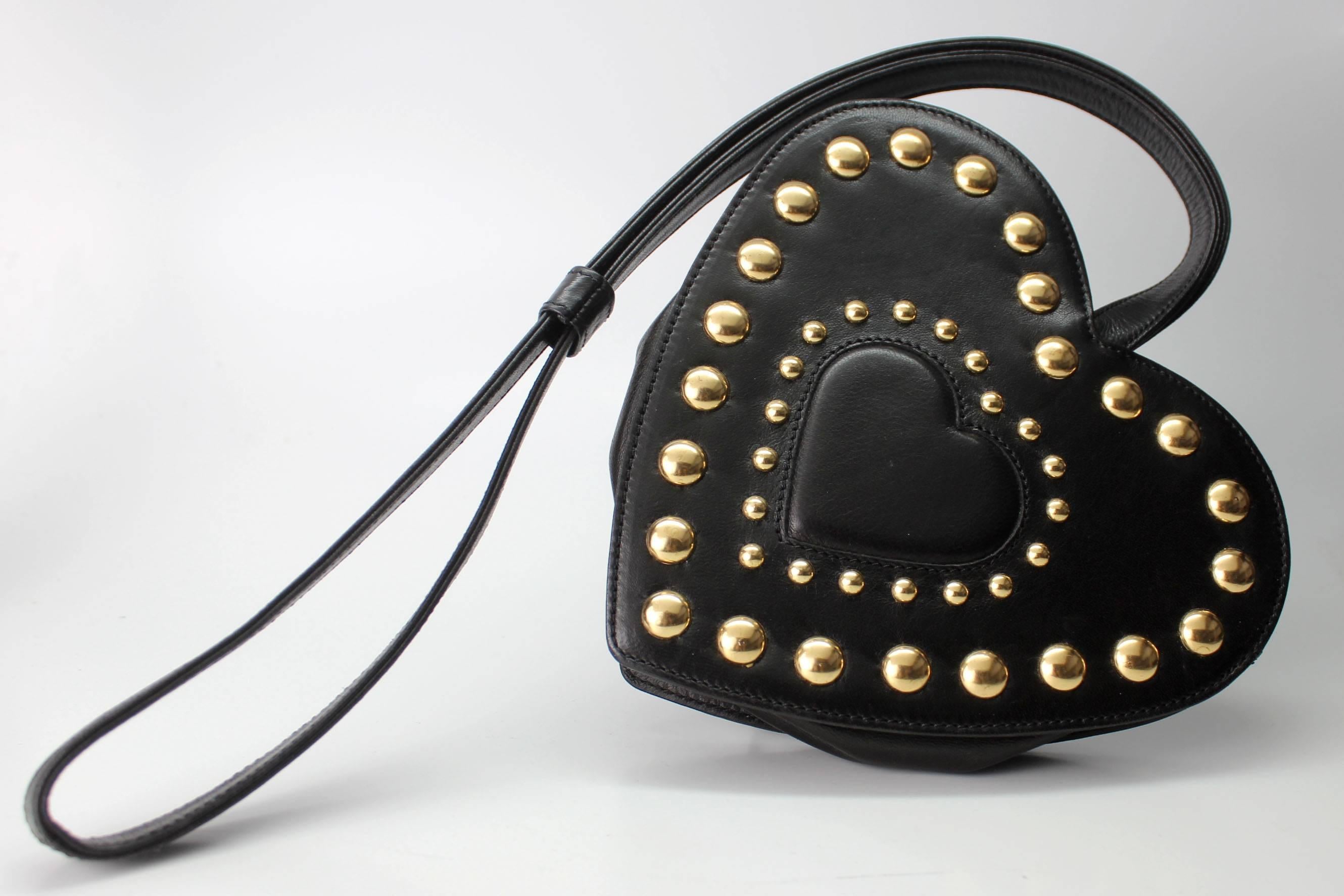 This 1980's handbag is pure Moschino with its whimsical design in the shape of a studded heart. It has a shoulder strap and folds flat but expands with enough room to carry essentials. It is stamped Moschino Redwall and comes complete with dustbag.