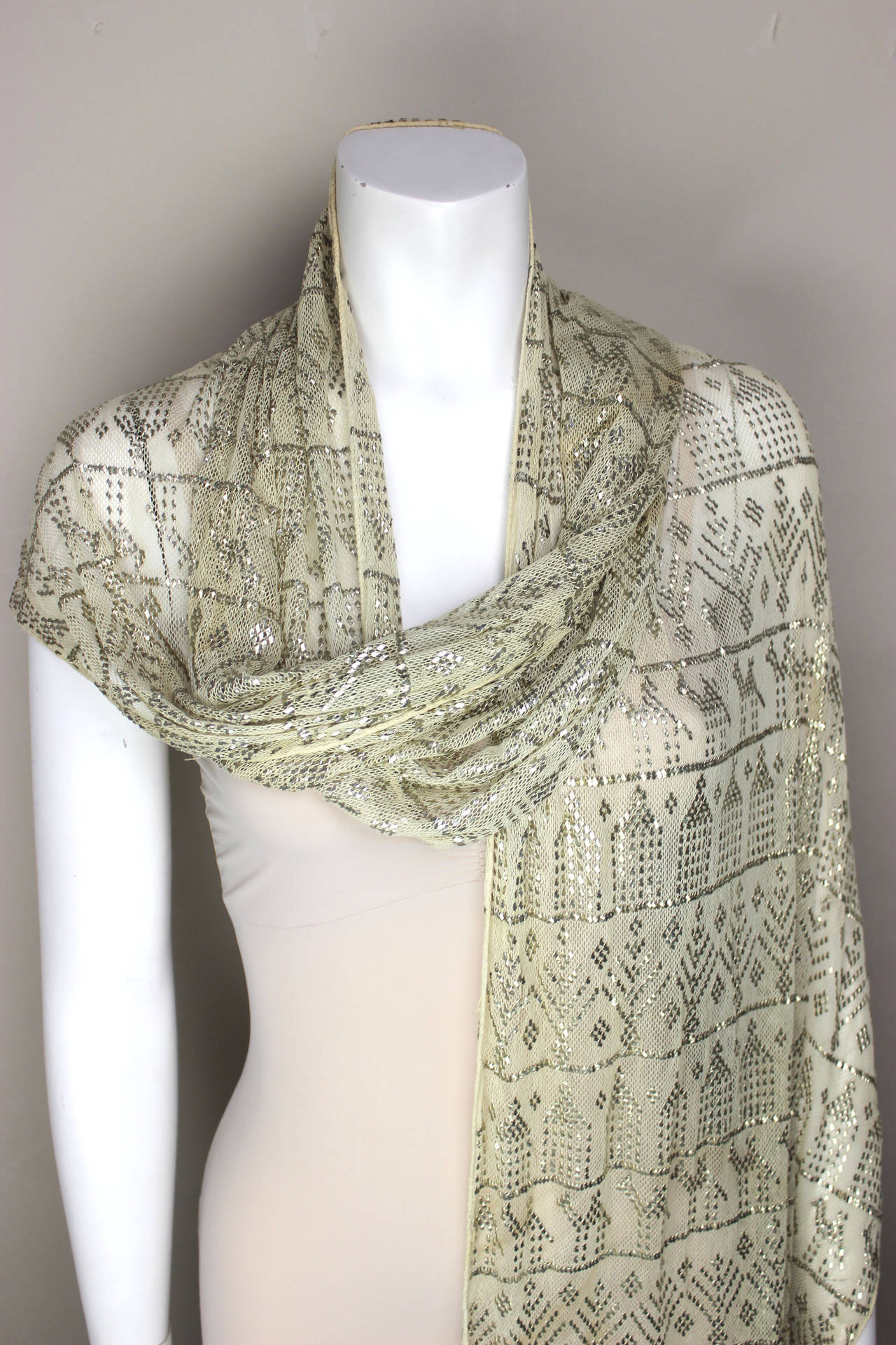 In the 1920's, Tutankhamun's tomb was discovered, sparking an interest in all things Egyptian. Metal embroidery dates back to Ancient Egypt. The flat stripes of metal are worked into a mesh fabric in various designs. This scarf is a warm creme color