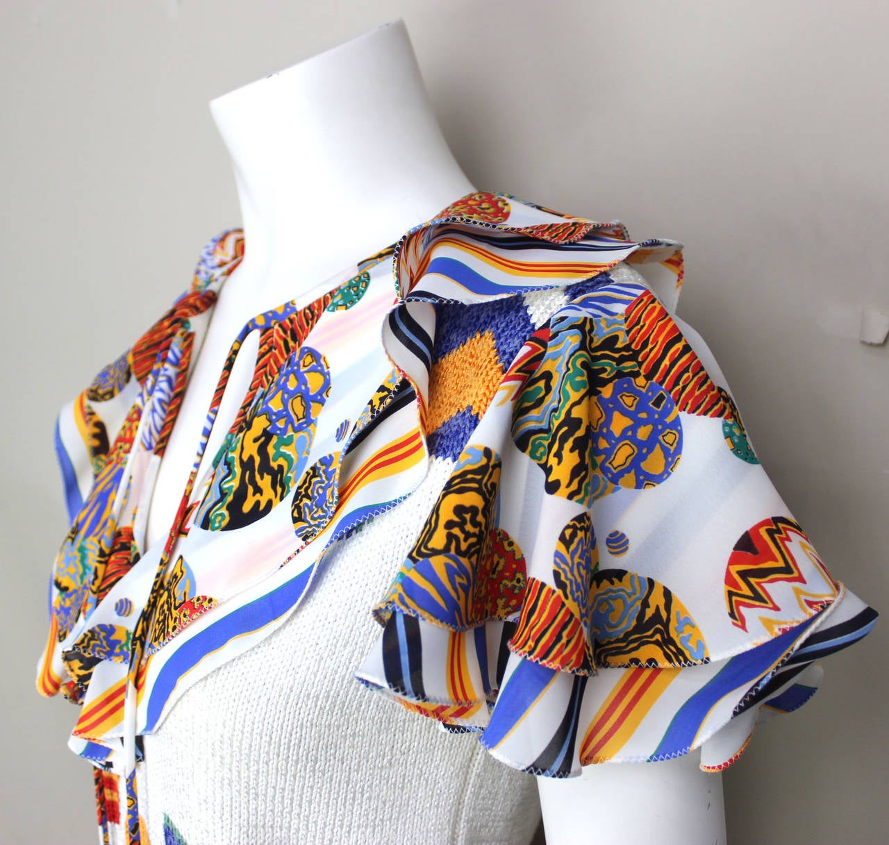The design of this top is very unique with its combination of a cotton knit body and rayon collar and sleeves. The pattern combines stripes, abstract designs, and geometrics. It closes with two ties trimmed with tassels. Very chic!

Approximate