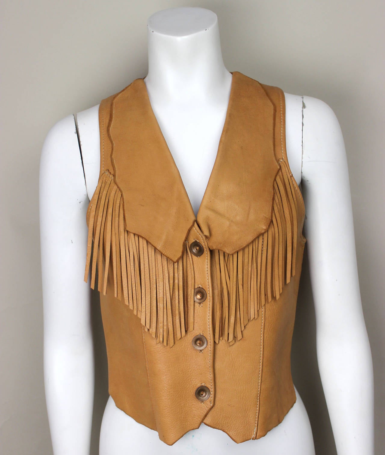This high quality vest was custom made in a supple leather. Its western inspired  features include beautiful fringe adorning the front and back. With fringed garments being the height of style this season, this fitted
vest is as relevant today as