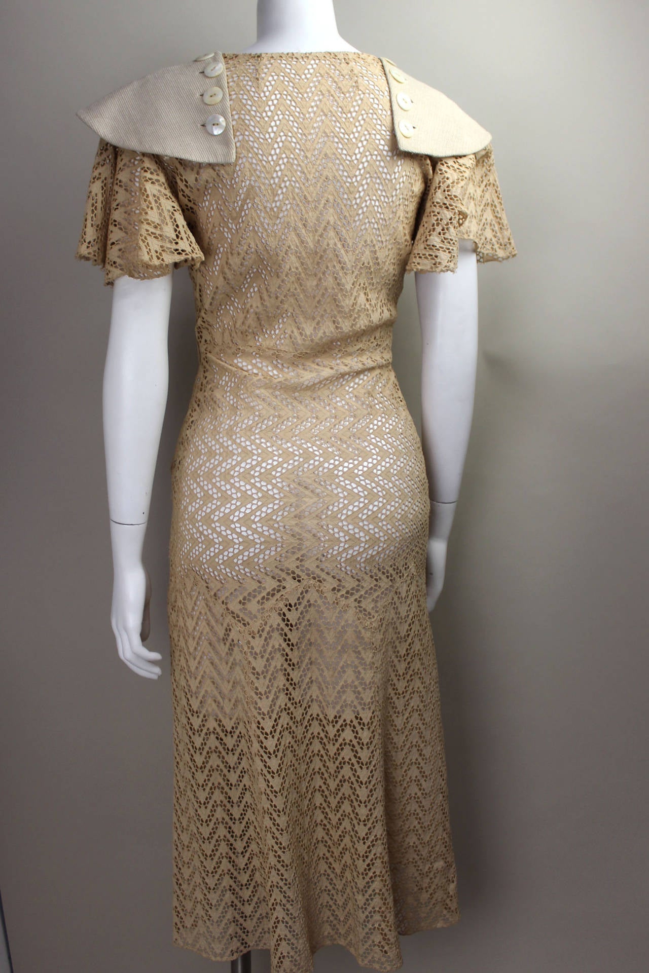 This dress is a rare find from the 1920's with stunning details. A butterfly sleeve is capped with a button on linen panel. The skirt has a slightly defined waist as well as a dropped hip panel with a slight flare, all in a lovely ecru.