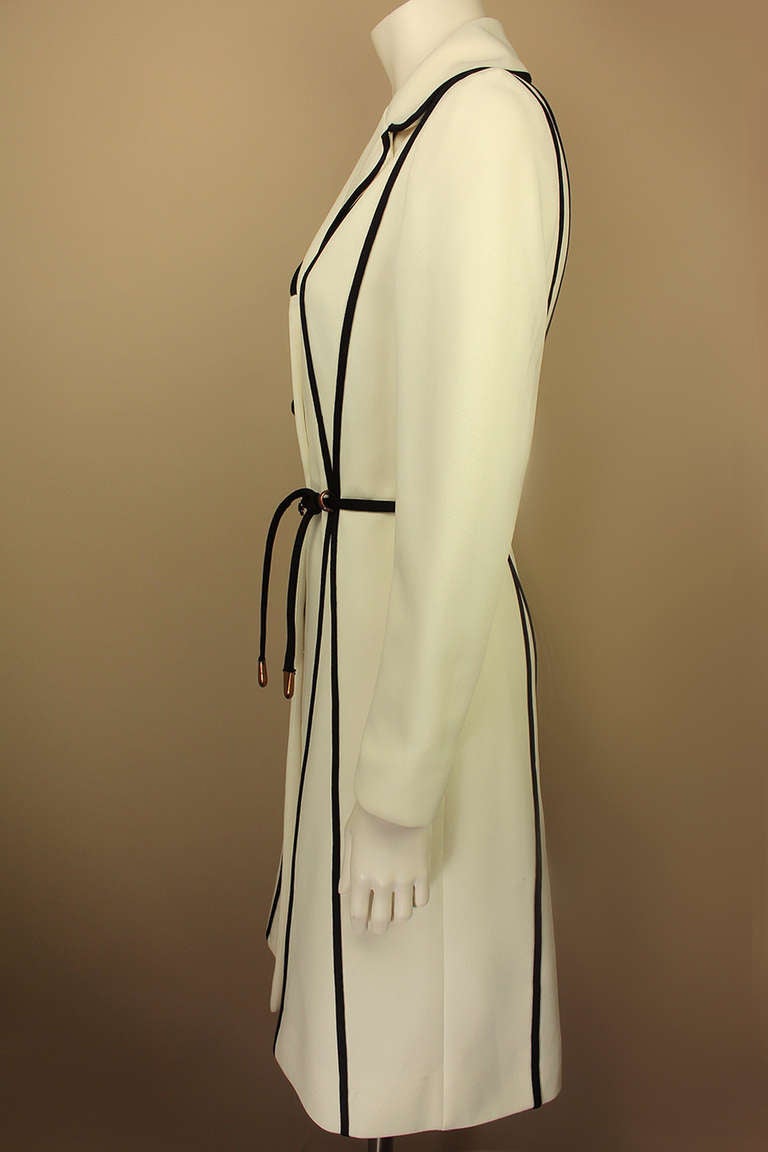 In the 1960's, the popular fashion brand Lilli Ann produced a mod-inspired line. This coat is of that era and an incredible find. It's a light weight white knee length coat with bold graphic details. It has vertical black trim resembling bold