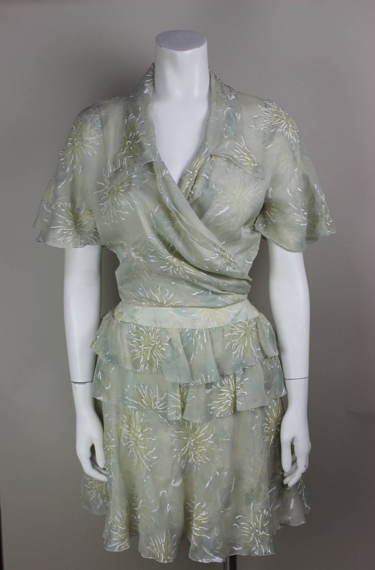 This lovely 100% silk two piece has a short ruffly skirt and a delicate wrap top with a butterfly sleeve. The pattern is a muted floral that appears to be hand painted. These two garments are versatile and can be paired with other clothing to create