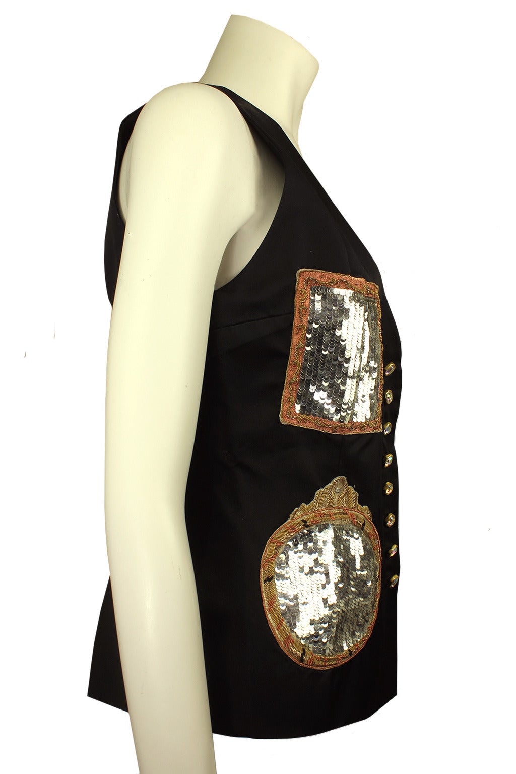 Todd Oldham always had clever design elements to his clothing. This vest has four large patch pockets that are silver sequined within gold frames mimicking baroque mirrors. The vest is hip length and has a satin tie back to cinch in the waist.