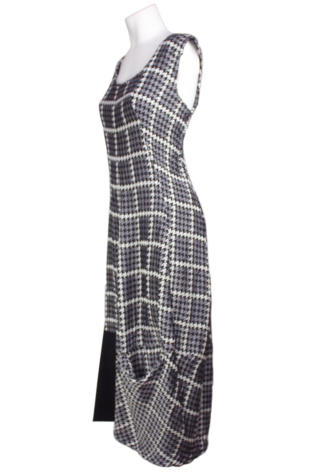 This dress is pure Comme des Garcons with a randomly seamed patchwork hem and pocket details. The dress is a black and white houndstooth print mixed with men's wool pinstripe suiting at the hem. The dress narrows at the bottom forming a cocoon shape.