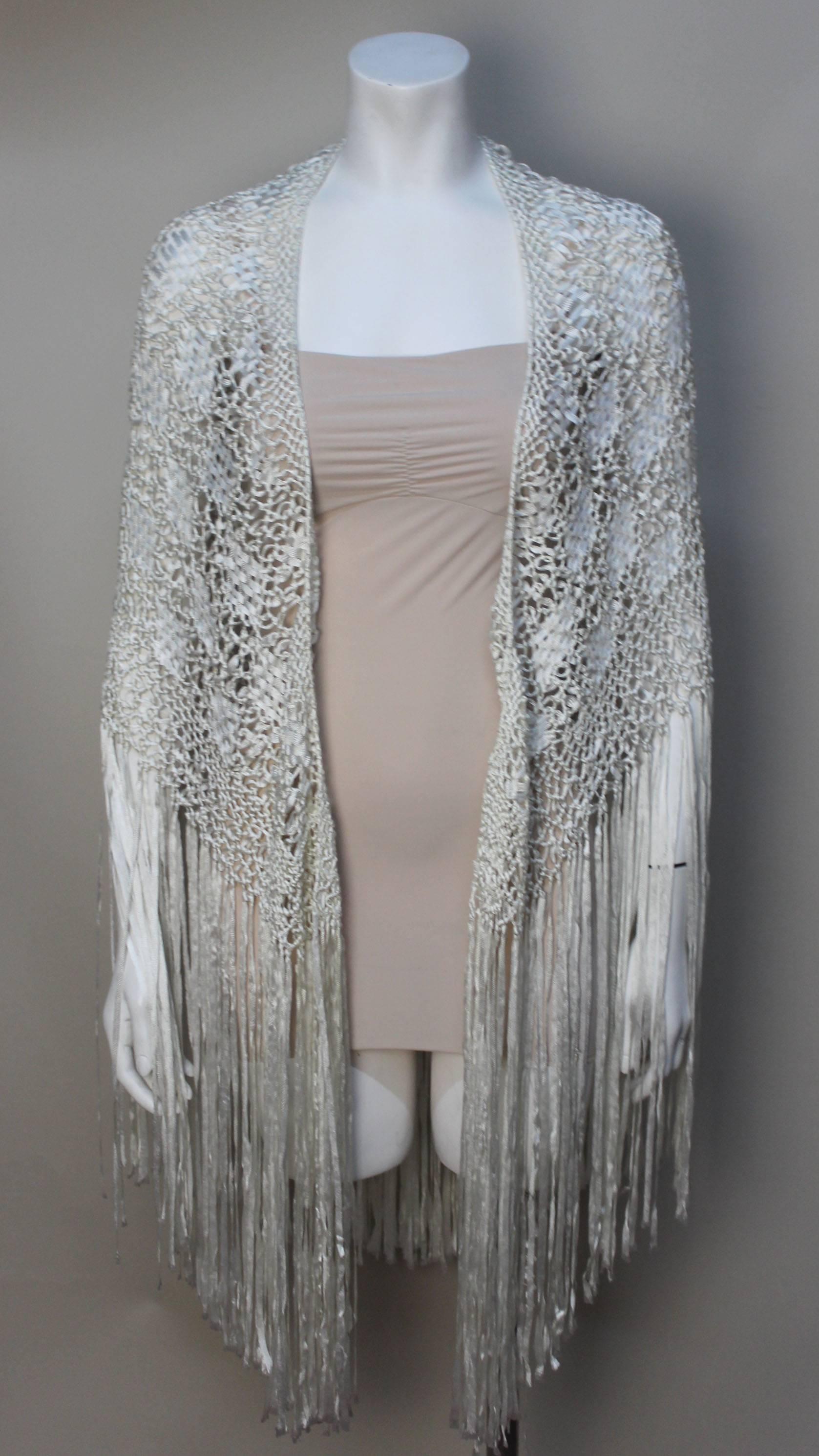 This white vintage ribbon shawl is beautifully rendered. The crochet is in an intricate pattern with long silky fringe. It wraps beautifully over the body or can be incorporated in home decor. 