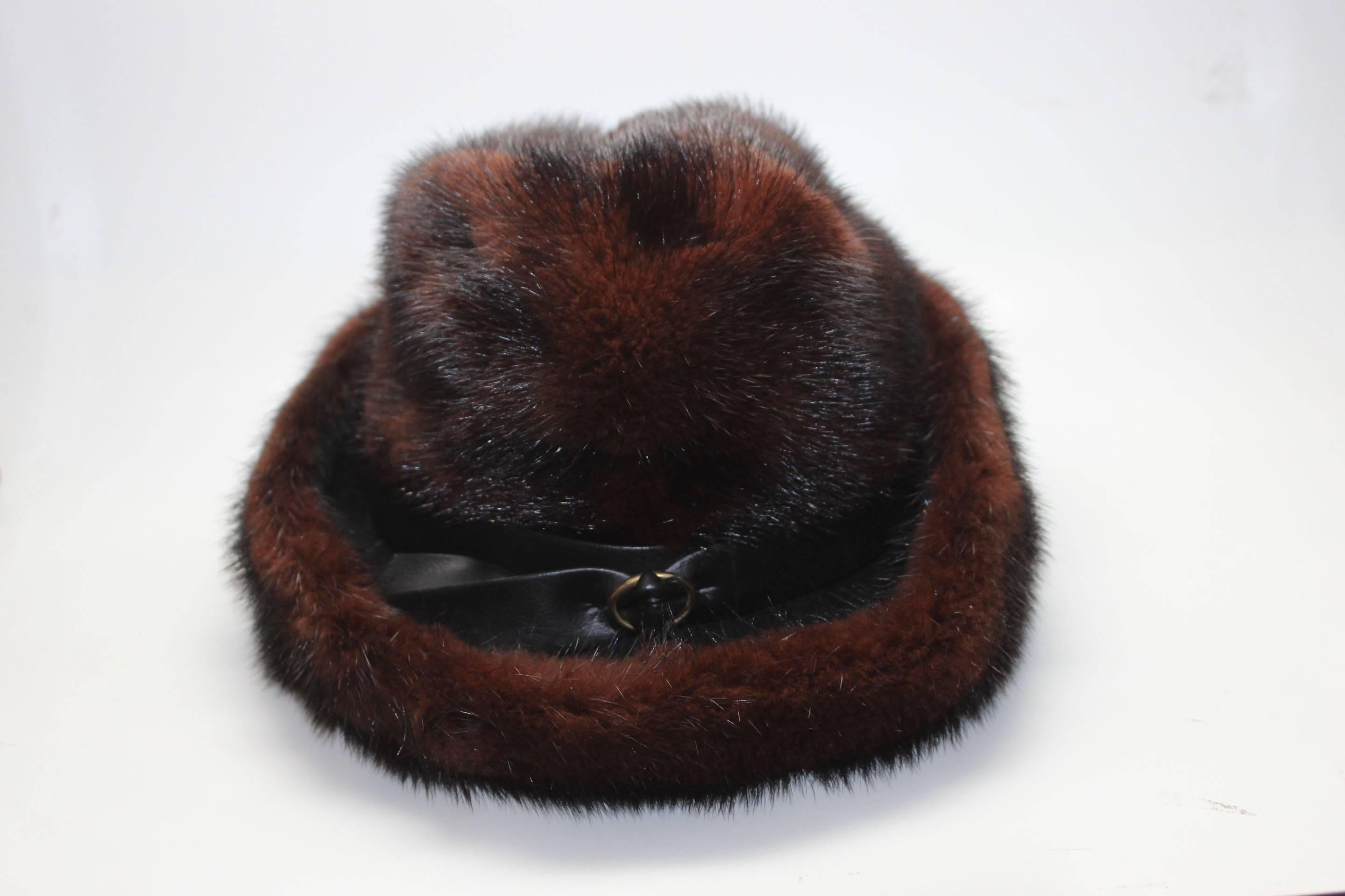 This mink hat has an unusual shape for the 1950s. Most common styles are pill boxes and close fitting shapes without brims. This hat appears to be based on a mens fedora. The mink fur is in a black/brown combination and can be worn with either
