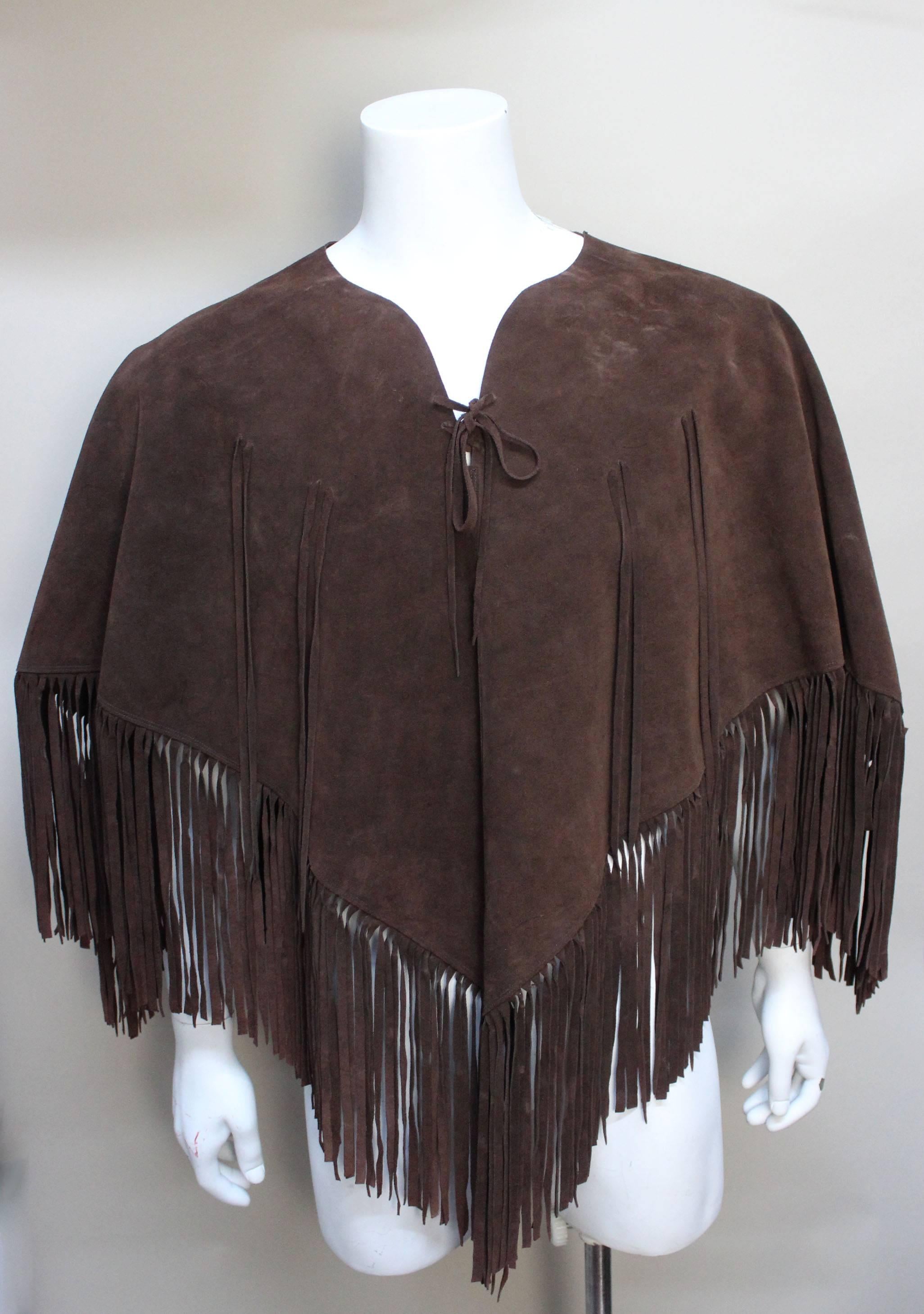 This rich chocolate brown suede poncho is pure 1970's. It is generously fringed and drapes beautifully. A rawhide tie keeps it closed at the neck and it is further embellished with additional fringe on the front. It measures as a 34