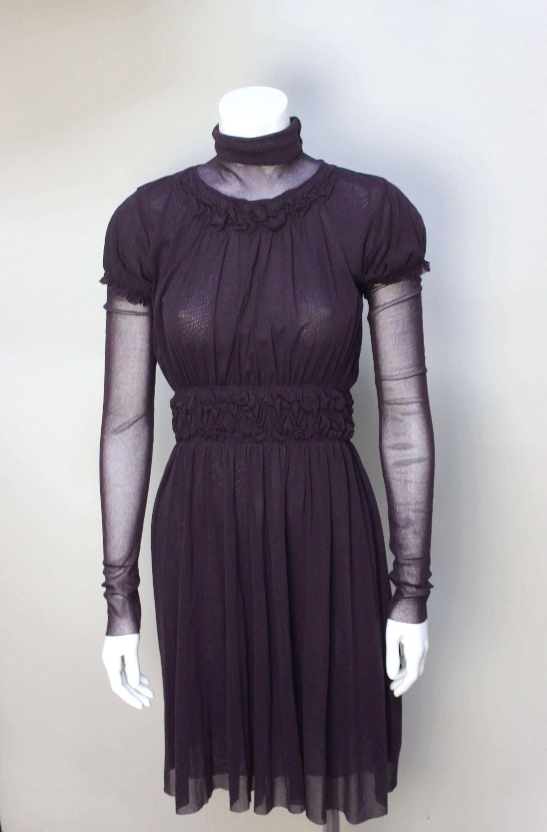 This Gaultier Solieil dress is layered in a playful manner. A very sheer neck insert can be pulled up into a high turtleneck. The body of the dress has puffed sleeves, a ruched waist in a double layer of mesh and long sheer mesh sleeves  that extend