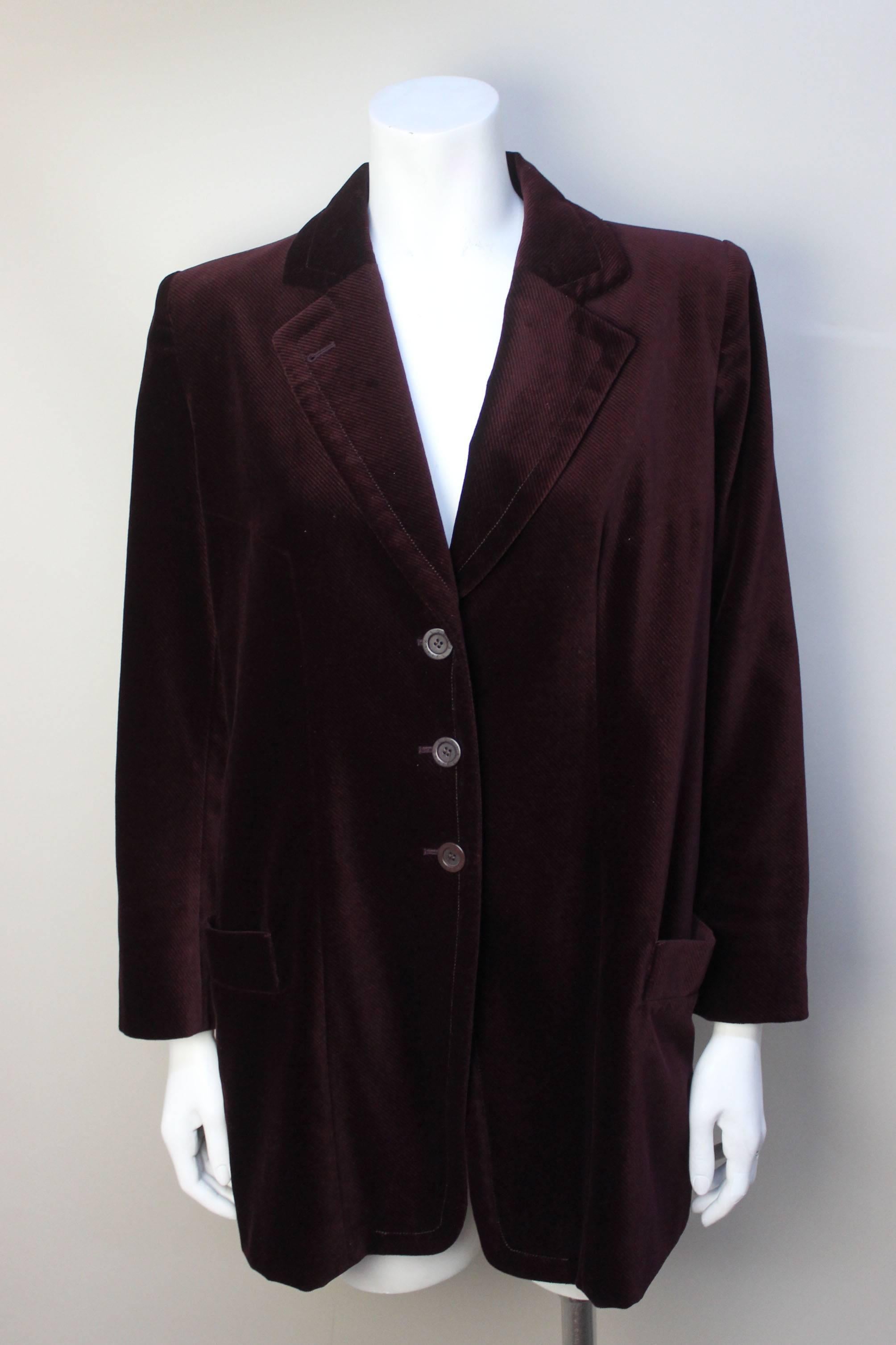 This lush burgundy velvet jacket is in the style of a mens frock coat. It has peaked lapels and two patch pockets. There is a nice added detial of four logo buttons on each sleeve. It is fully lined in a fine salmon pinstripe rayon. 