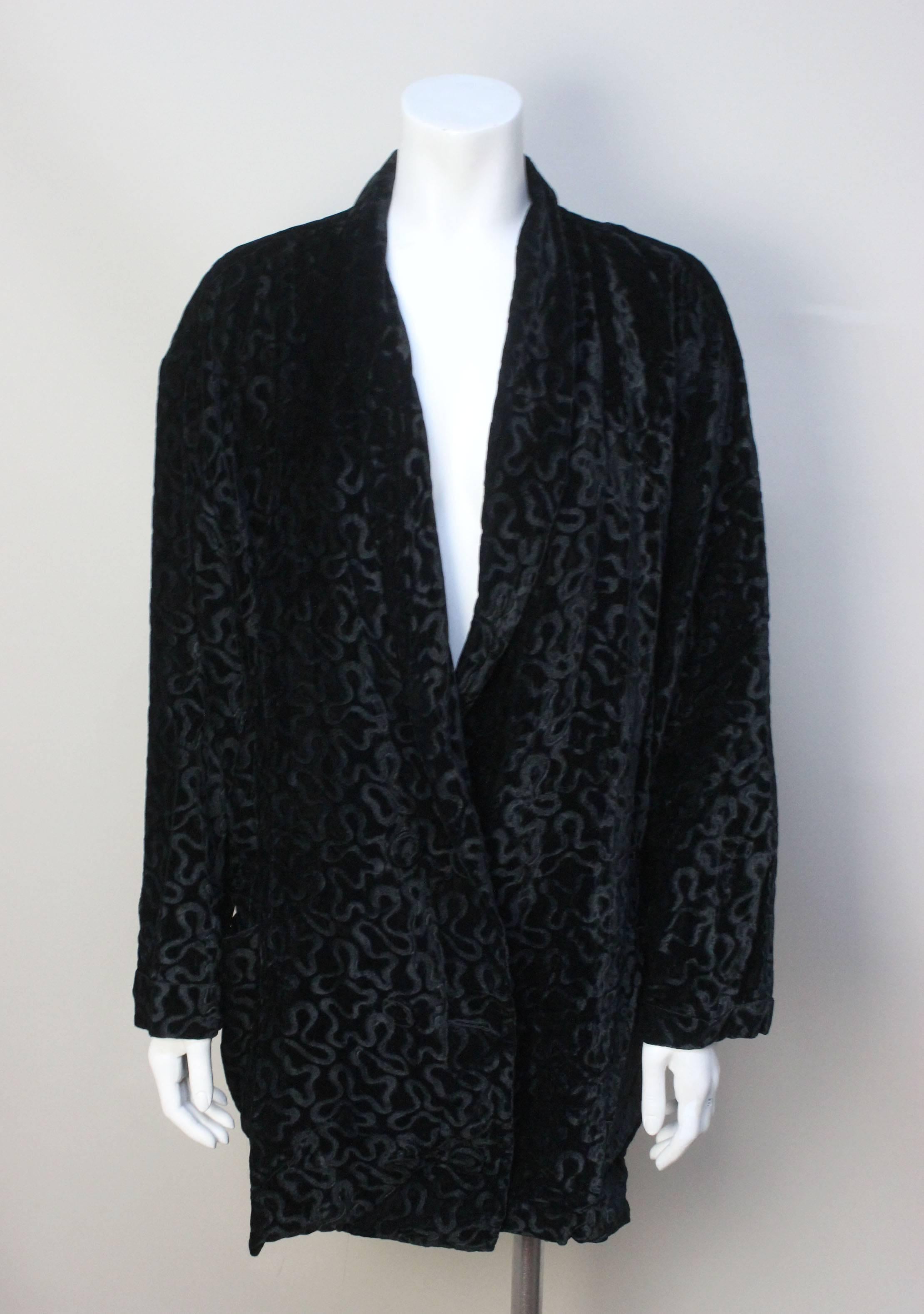 This jacket is a wonderful Norma Kamali design. The style is pure 1980's but very relevant to today's fashion. The fabric is a black inky burnout velvet in a swirl pattern. It has a long shawl collar with low double breasted buttons. Two large patch
