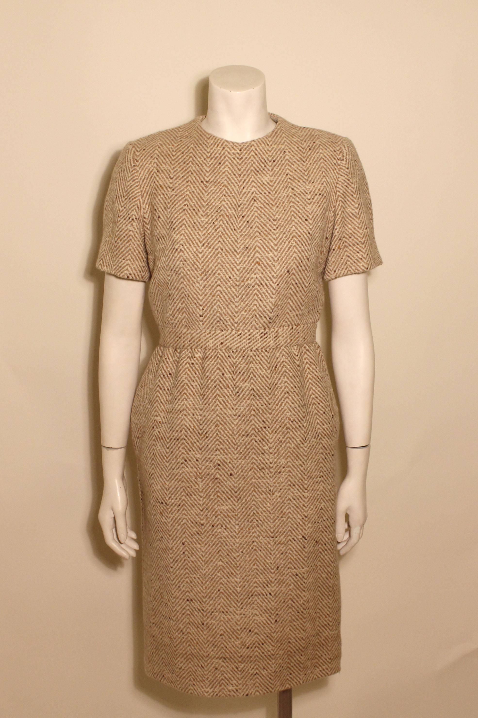 This tan tweed Trigere dress includes a banded waist and short sleeves. The chic covered buttons of the tweed dress are down the back. It has a full silk lining. 