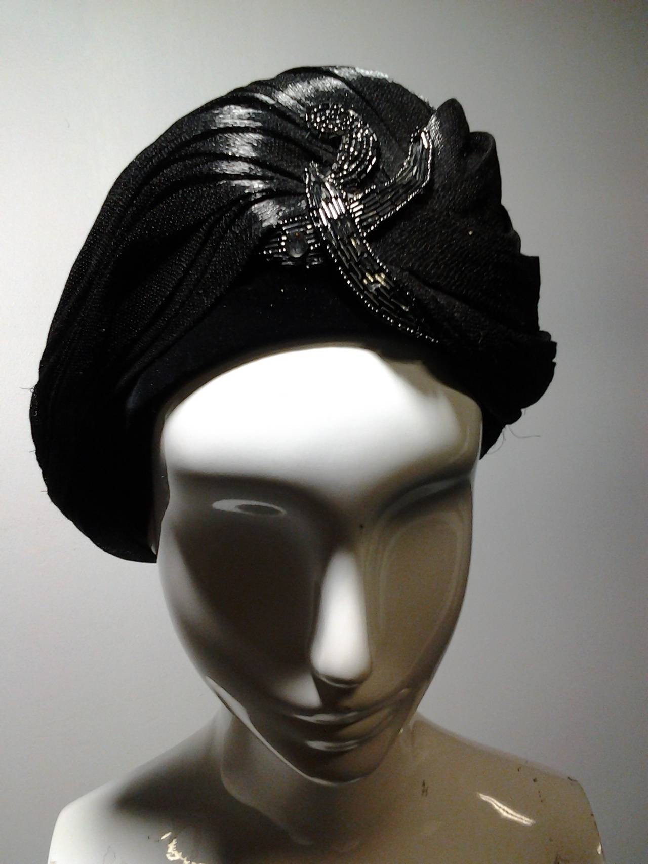 1960s dramatic Dior black laquered straw turban with off center front beading and velvet band.  Measures 22
