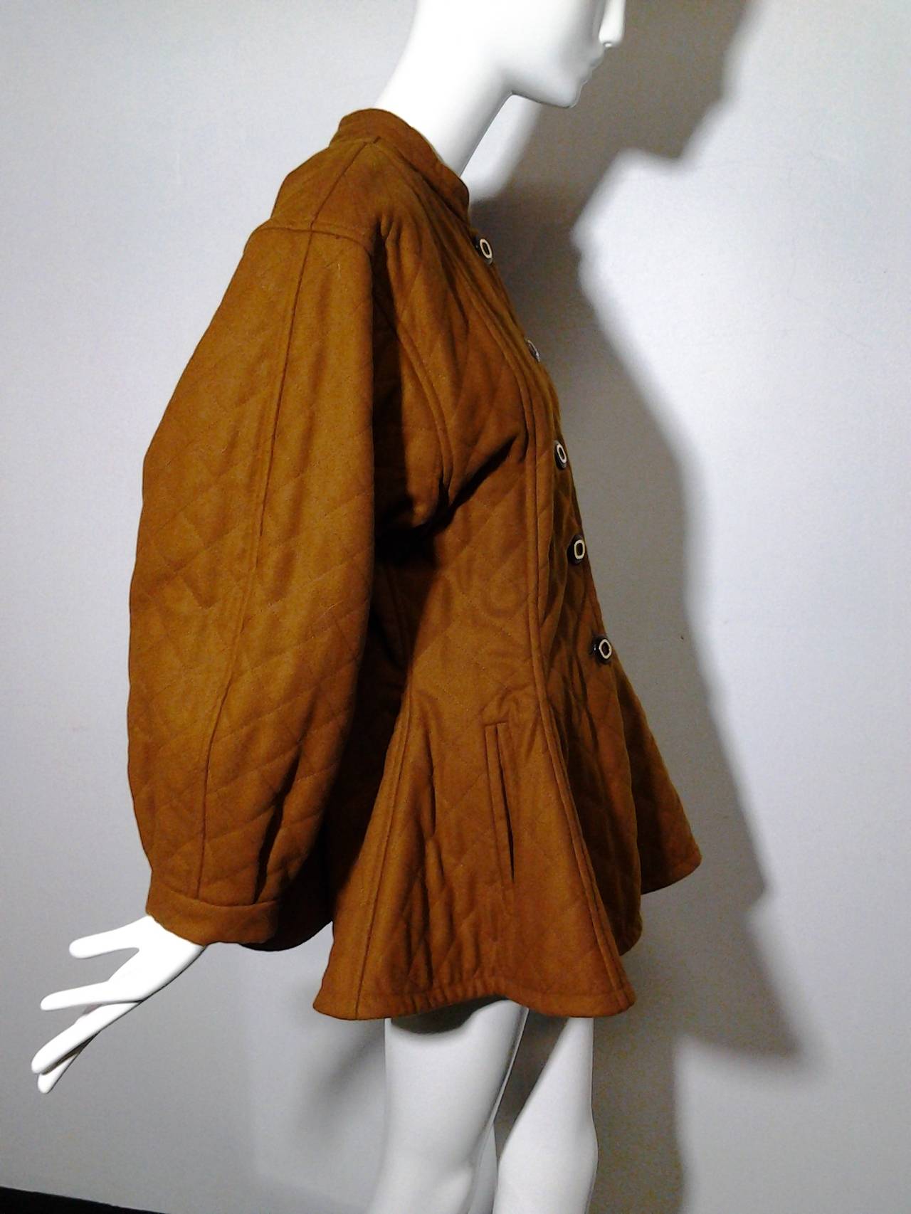 1980s Yves Saint Laurent quilted wool Moroccan-inspired wool coat:  felt-finished, nutmeg-color with peplum.  Real leather button front.  Inner lining is quilted with braid edge trim.  Balloon cuffs and front slash pockets.