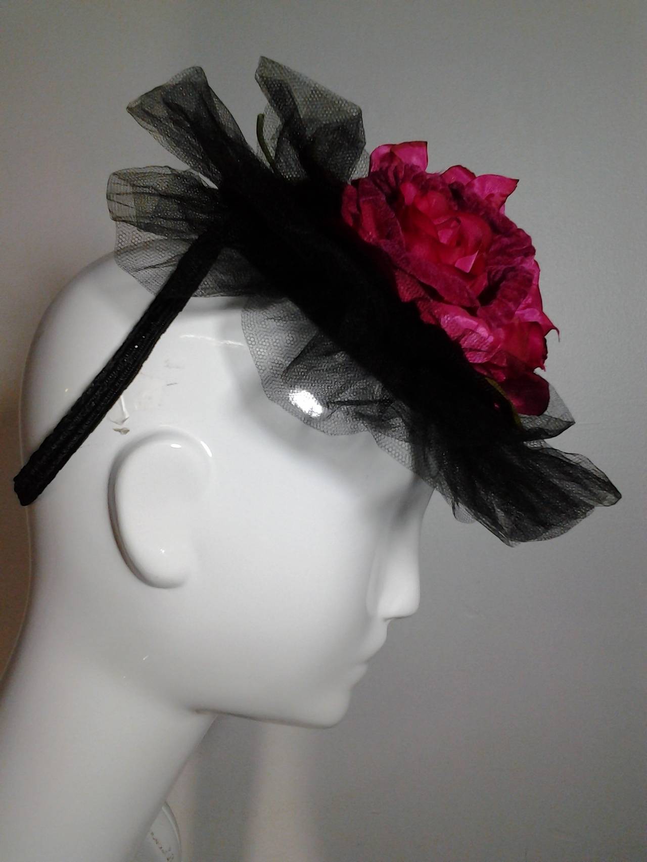 1940s black straw tilt hat with back loop for securing to head and trimmed with extravagant black silk tulle and bouquet of fuchsia silk roses.