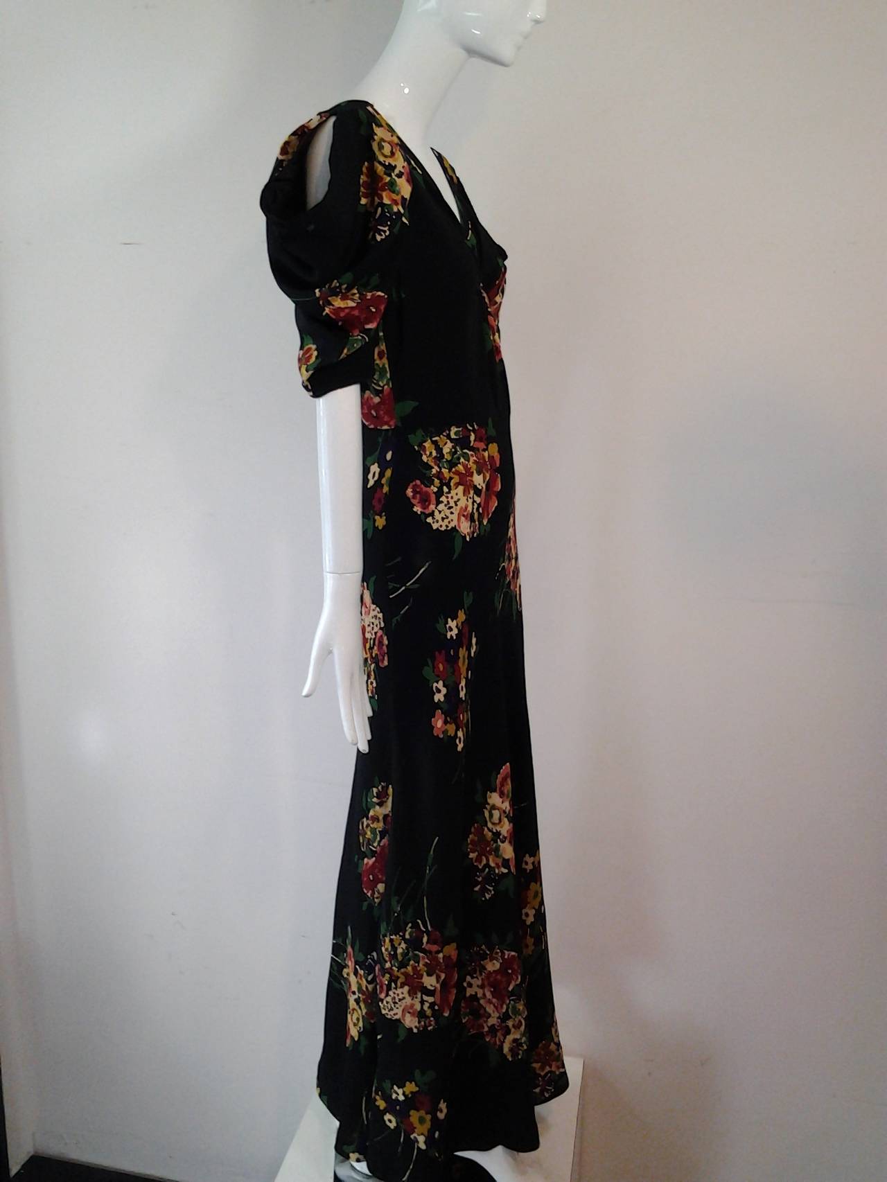 A wonderful 1930s bias-cut rayon floral print gown with center back buttons and draped peek-a-boo shoulder treatment.  Side snap and hook and eye closure.