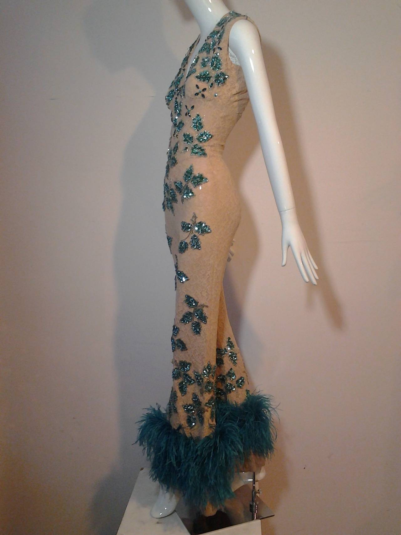 A fabulous 1960s Burlesque-style nude stretch lace jumpsuit:  Fully lined with sequin bead and rhinestone leaf and floral appliques in emerald green.  Pant hems are lavishly edged in turquoise ostrich feather trim. Zips up back, no bones.
