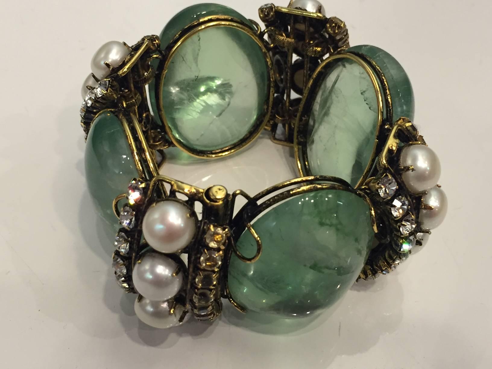 A gorgeous Iradj Moini massive cuff bracelet with large green cabochon quartz pieces hinged with pearl, topaz and clear stones set in gold-tone Indian-style antiqued setting.  Slide bar clasp.  2