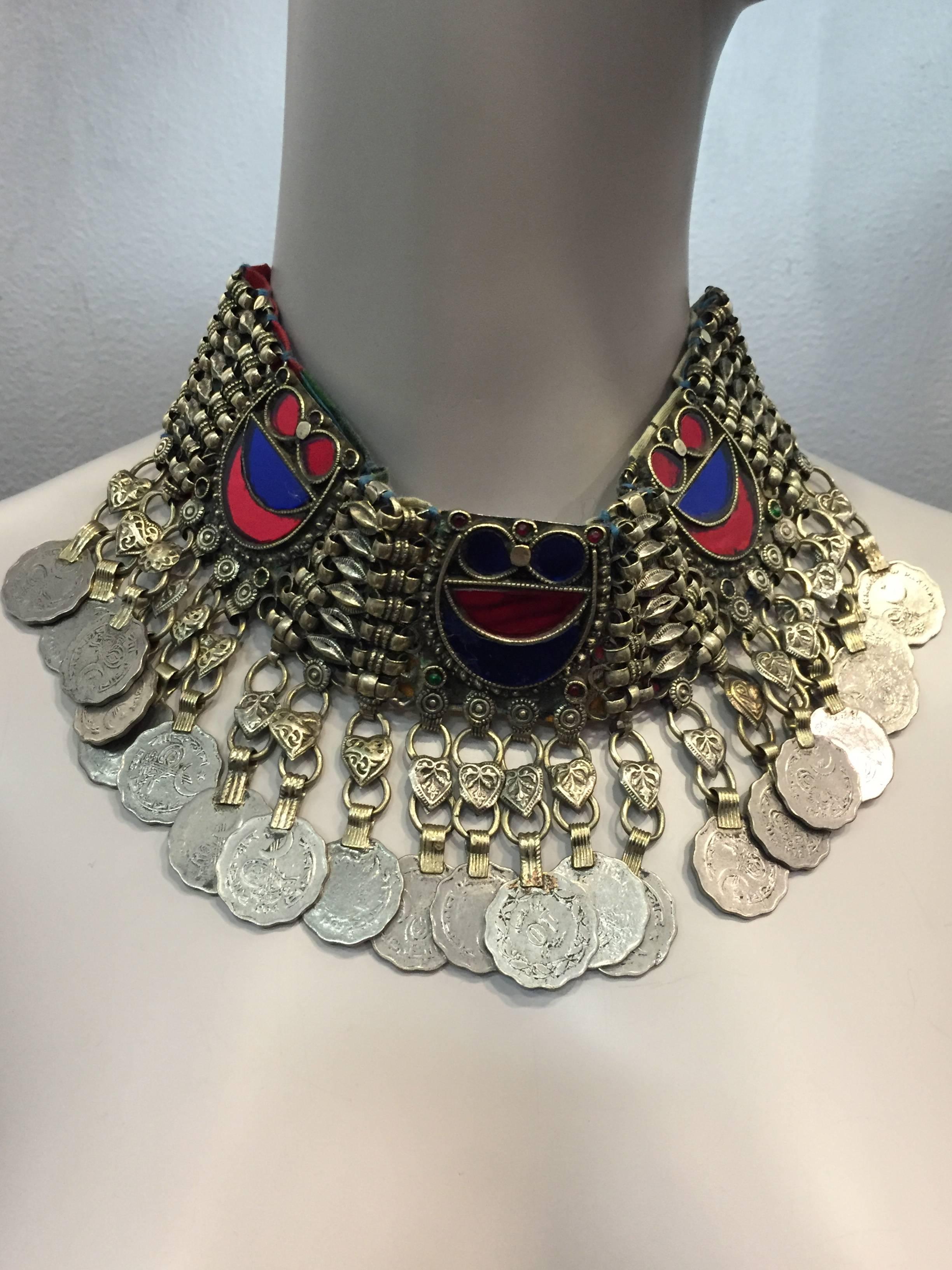 Ethnic coin bib necklace with tinted mirror tile inlay.  Closure is chain and hook.  Back is covered in back for smooth comfort.  Size is variable. 