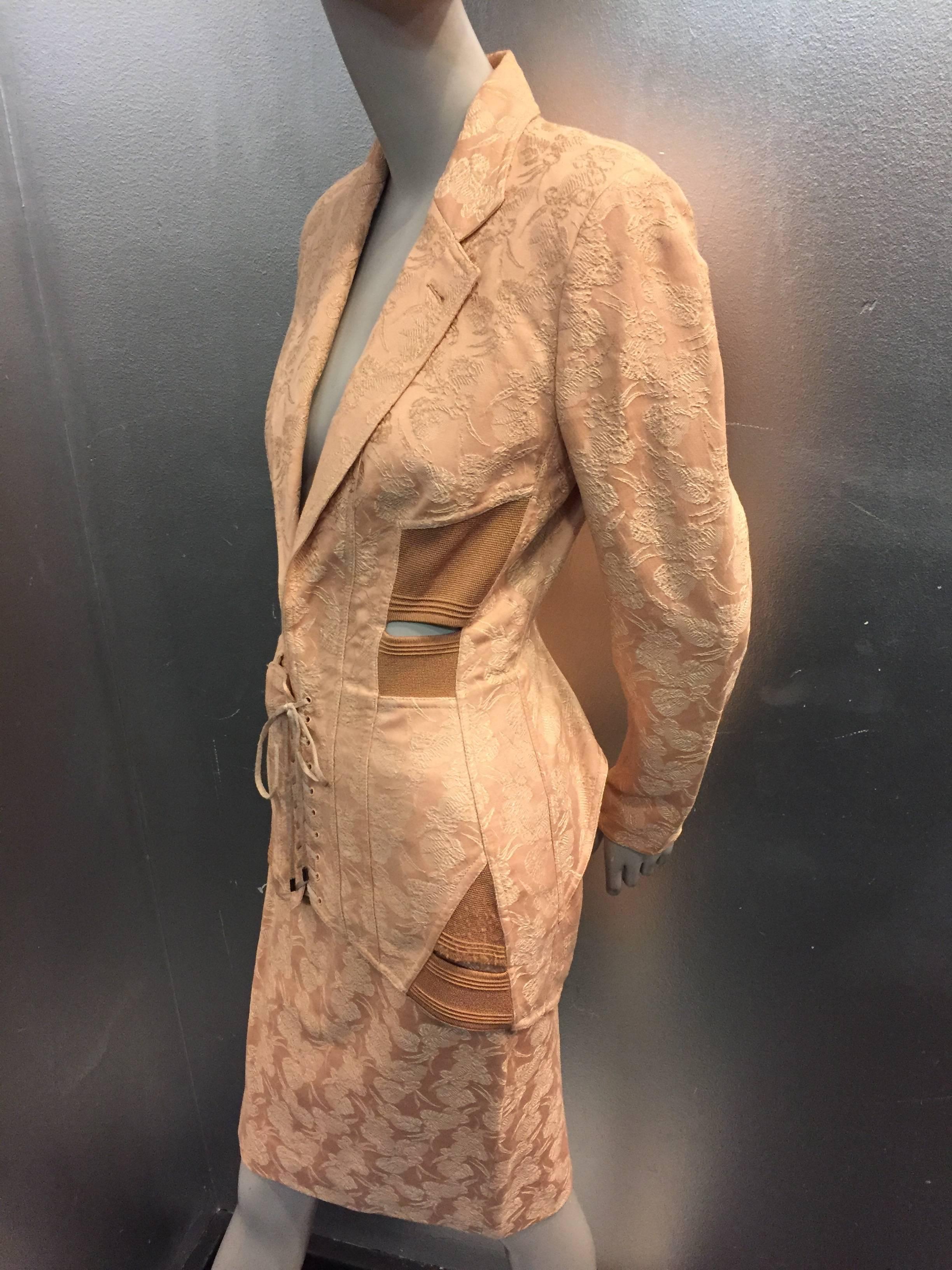 1980s Iconic Jean Paul Gaultier peach jacquard corset-inspired mini skirt suit. Flared peplum/girdle styling, back elasticized cut-out. Front corset lacing closure at jacket front.  Mini skirt with elastic insets at side and back slit. 